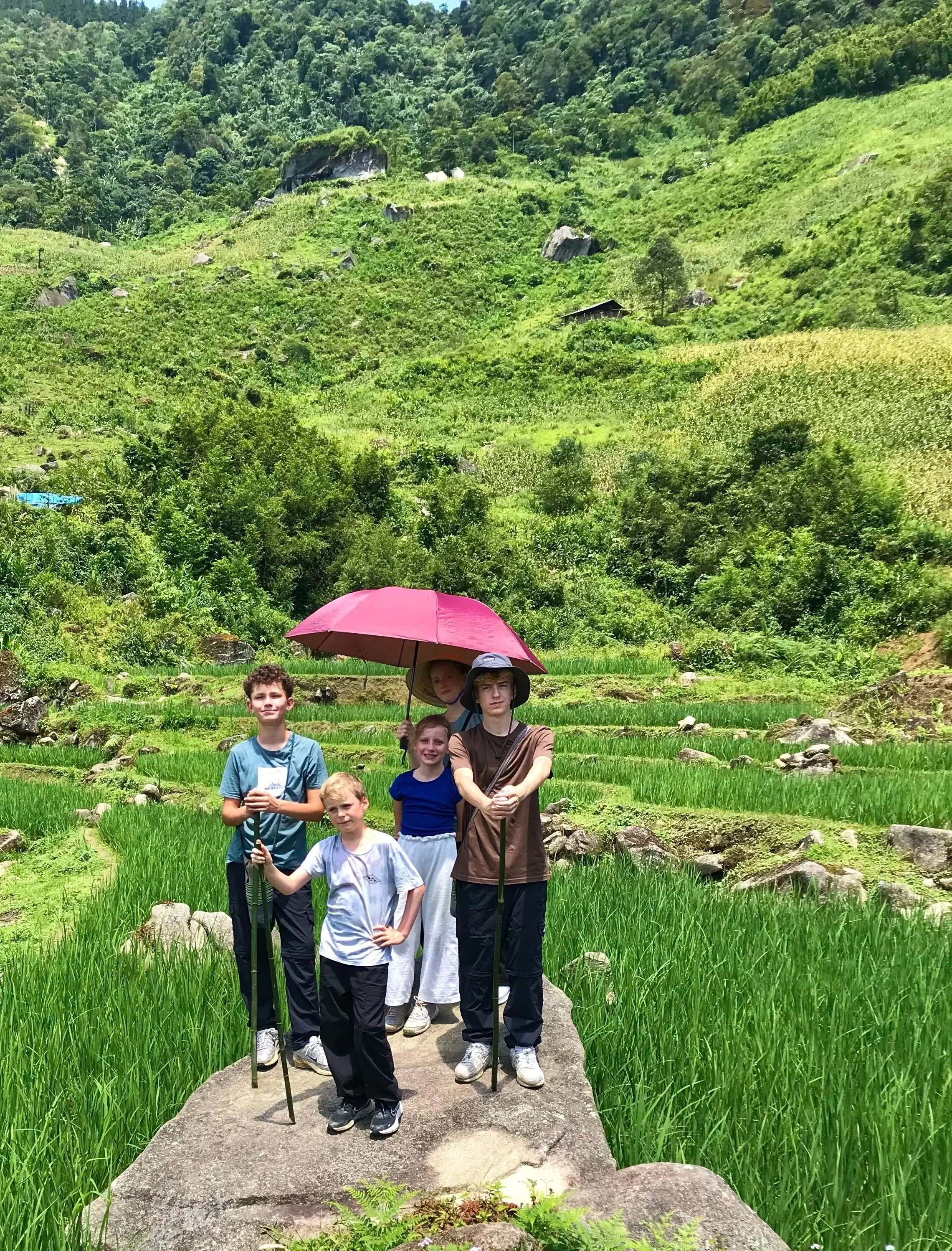 Family standing on rock overlooking rice terraces in Sapa