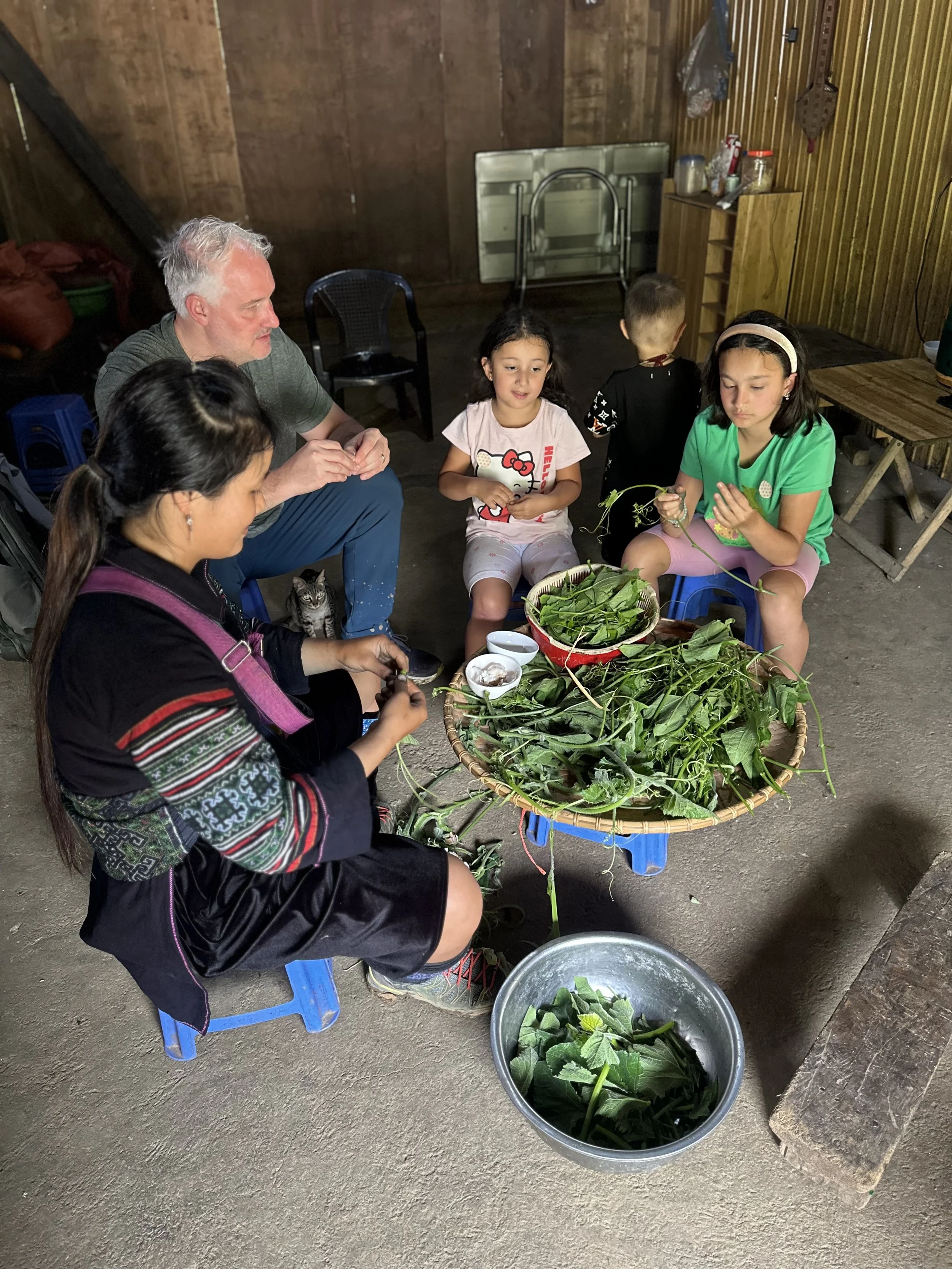 Family preparing vegetables with local host in traditional home