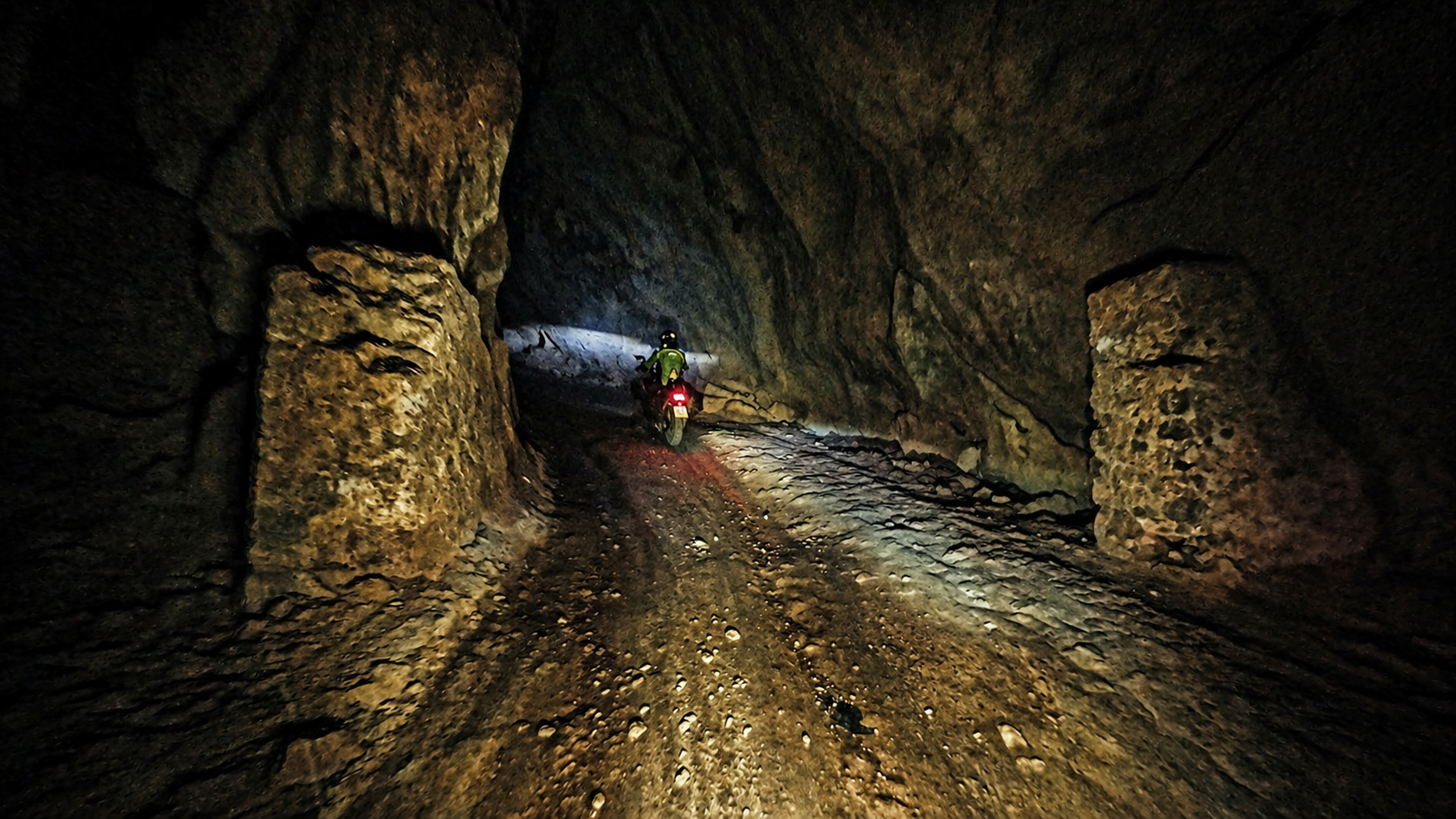 Motorbike riding through a narrow underground road tunnel in remote northern Vietnam with low light and rough surface conditions