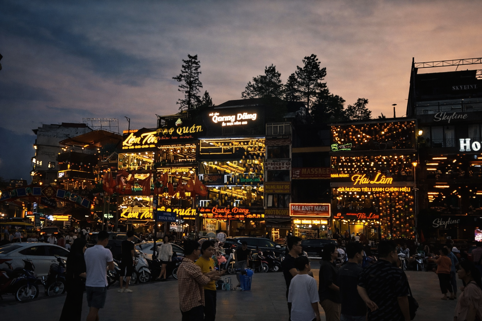 Colourful restaurants and bars glowing with neon lights in Sapa at night, with people walking and socialising along the street.