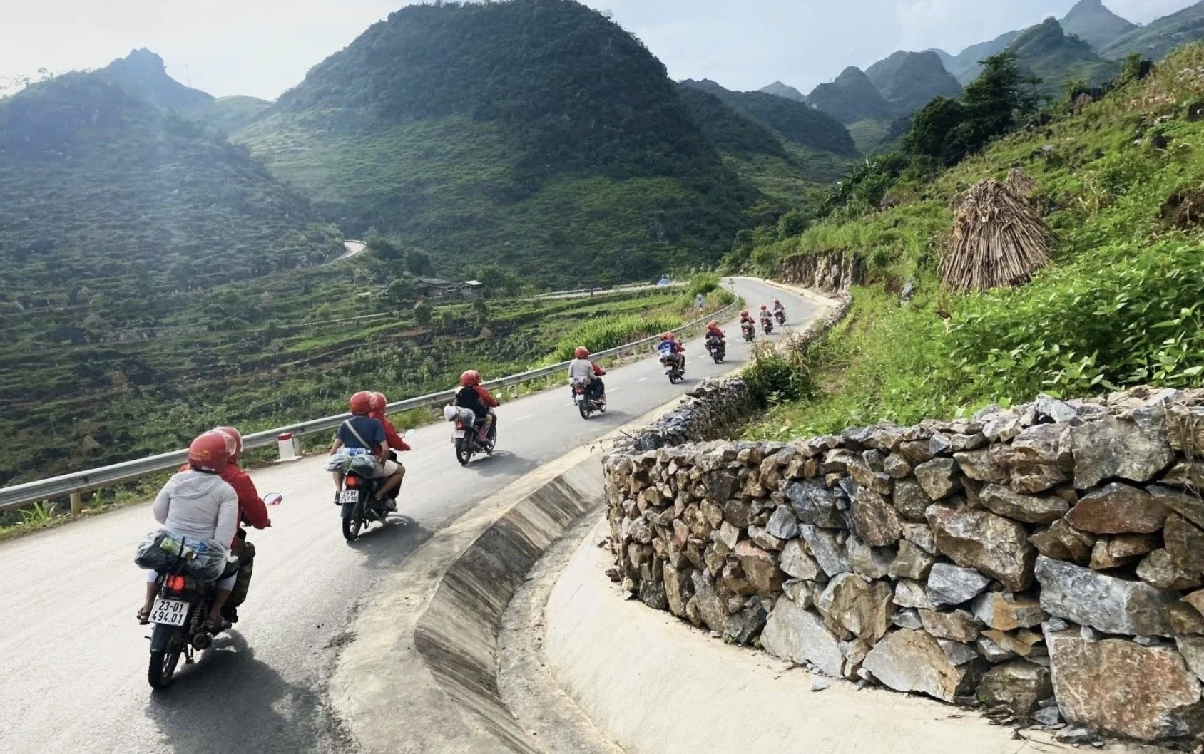 Motorbike riders traveling along a winding mountain road on the Ha Giang Loop in northern Vietnam