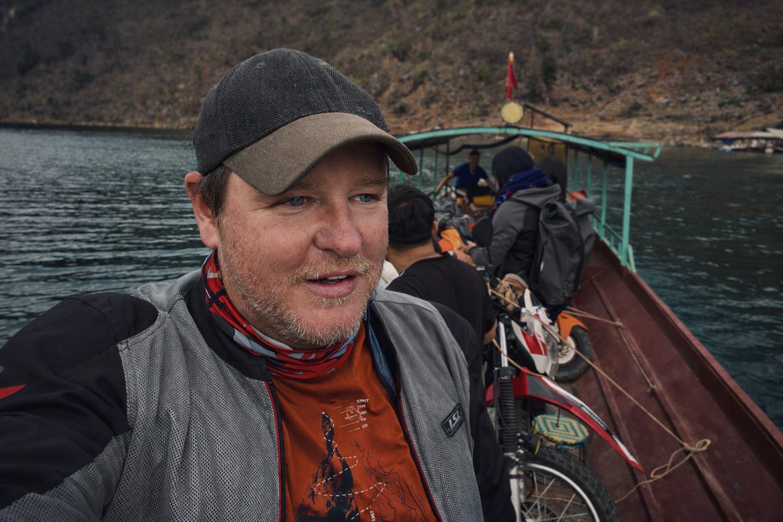 Traveller with motorbike on a small boat crossing a lake during a journey through northern Vietnam.