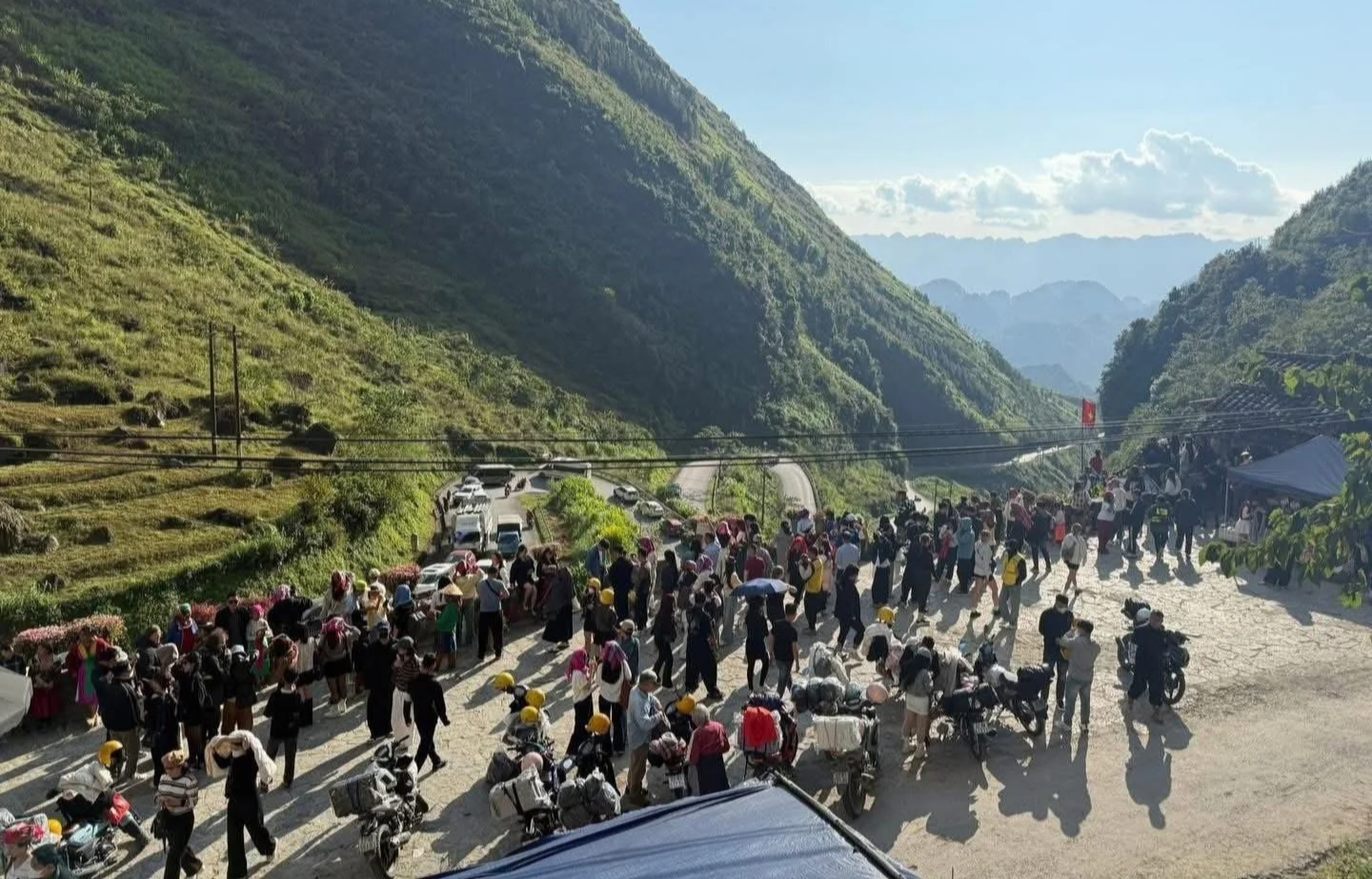 Large group of travellers and motorbikes gathered on a mountain pass road on the Ha Giang Loop