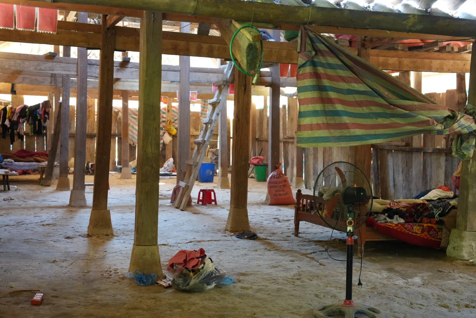 Rural Hmong family home near Sa Pa, showing a simple timber interior and the house surrounded by mountain vegetation.