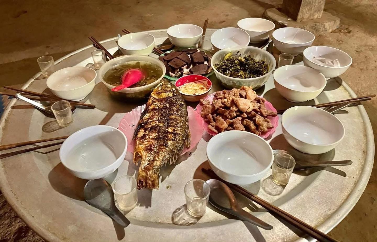 A traditional Hmong family-style meal served on a round tray with shared dishes and bowls.