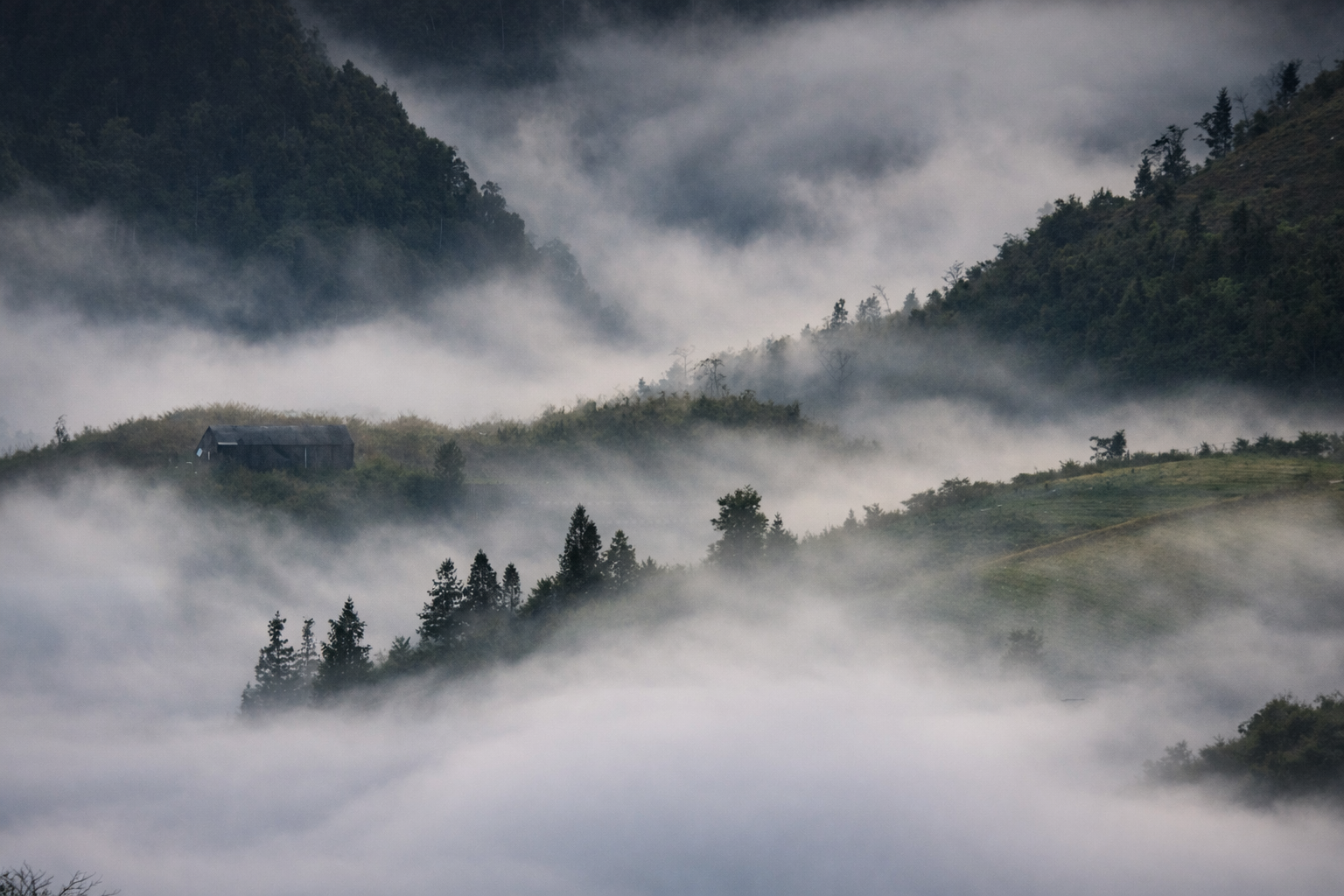 Fog rolling through a mountain valley with villages and terraces in Sapa.