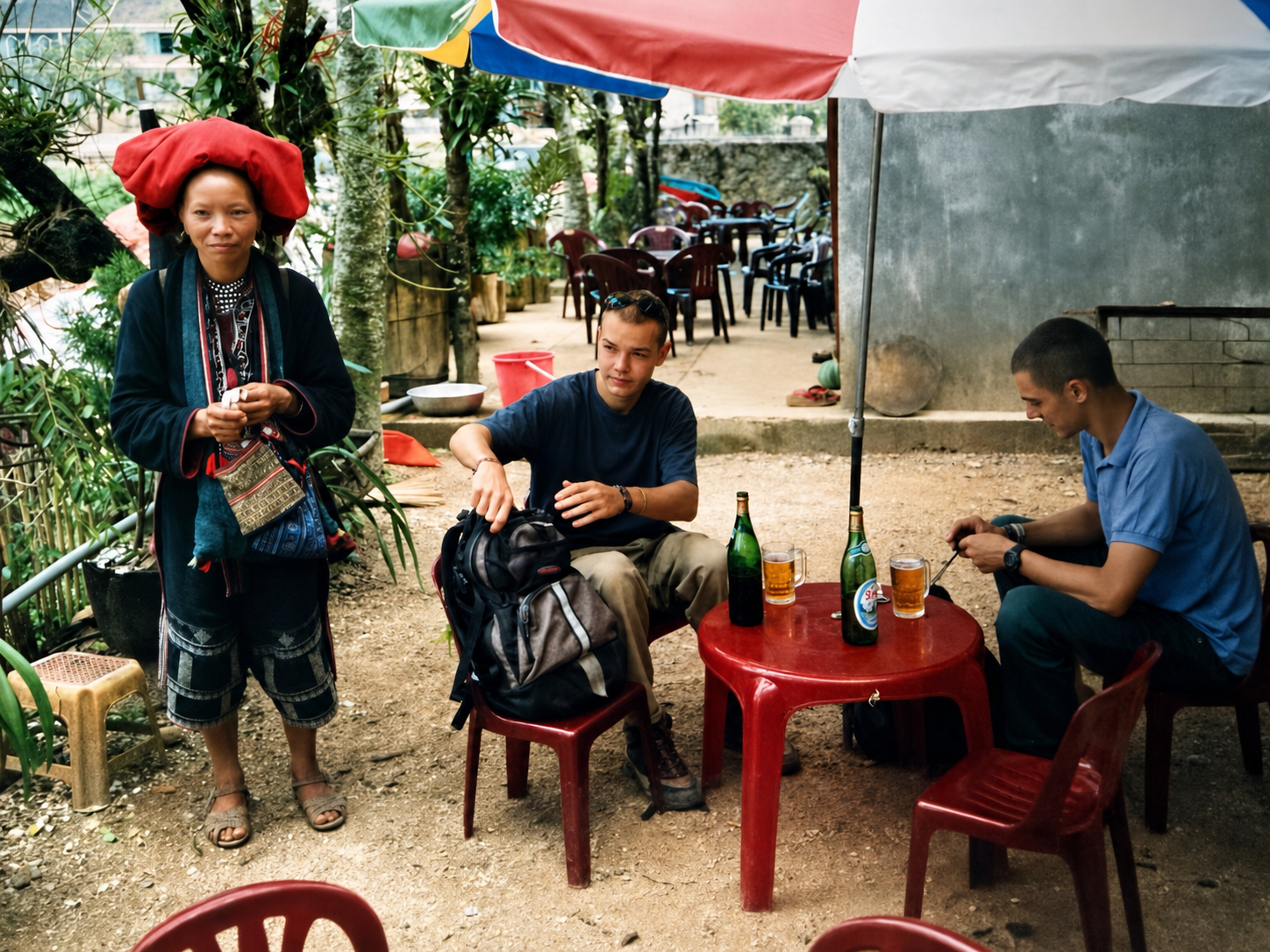 Dao woman talking with two Frontier team members seated outside a small café in Sapa, northern Vietnam, in 1998.
