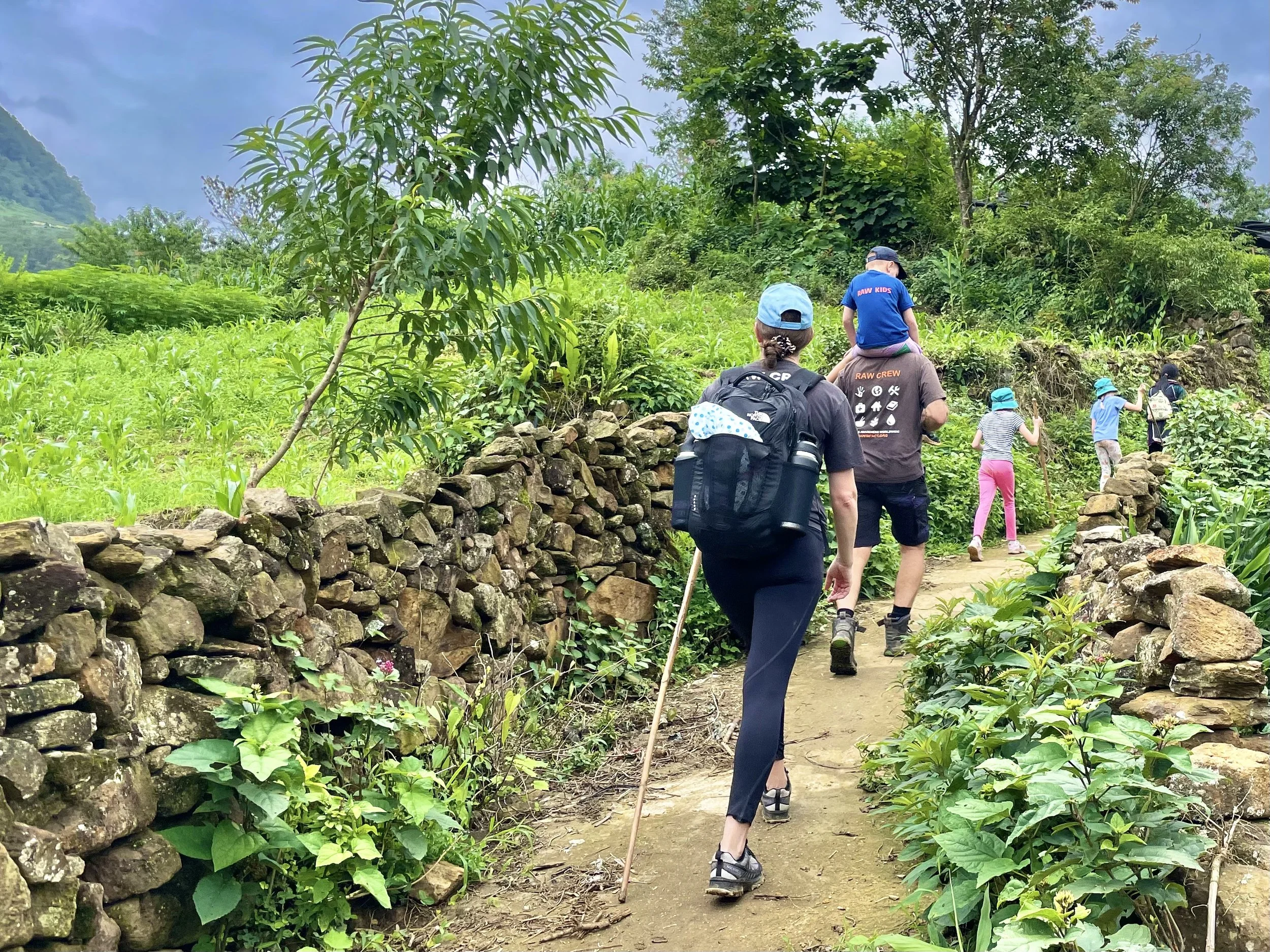 Family trekking along stone path in Sapa village