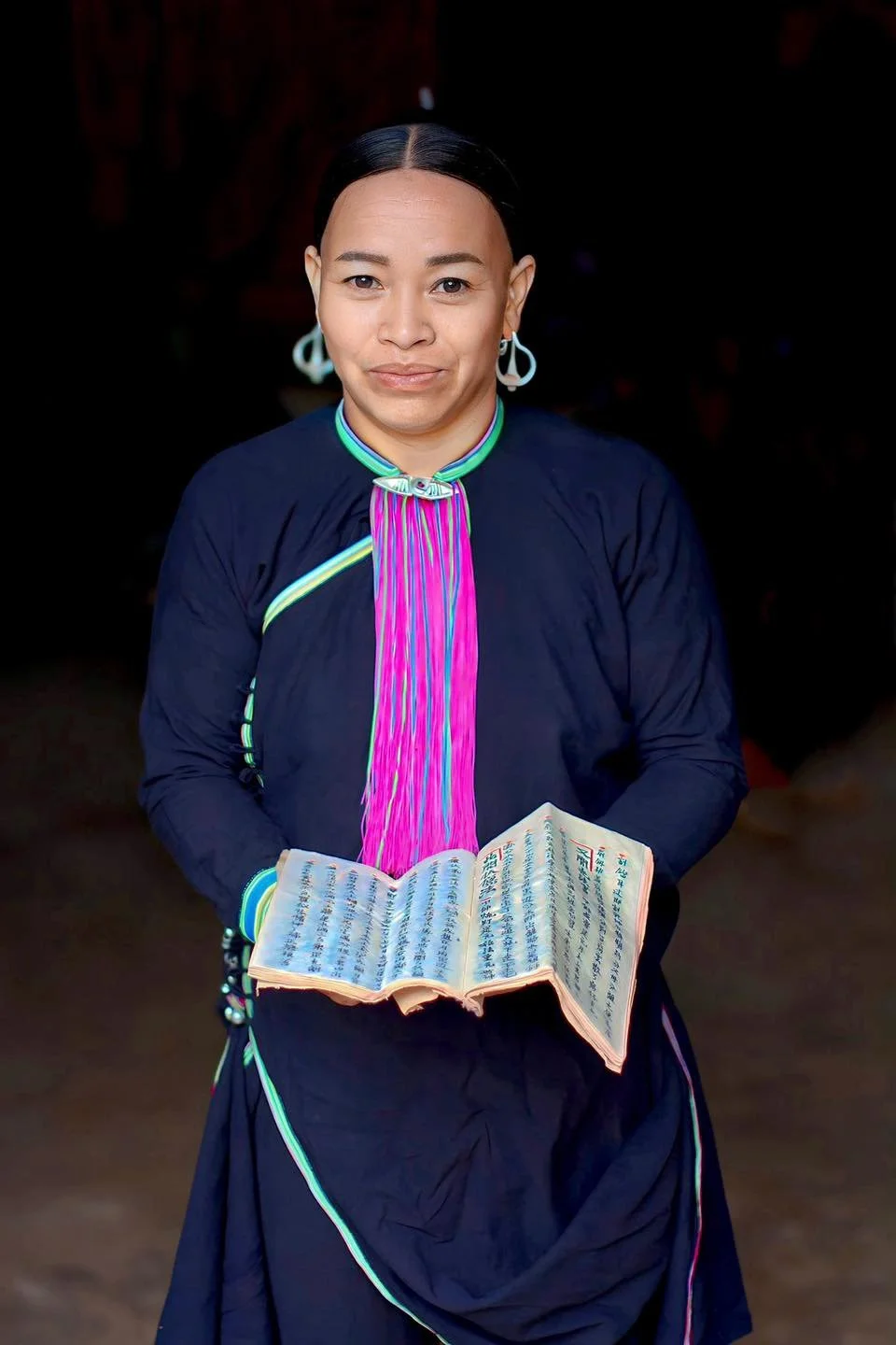 Dao woman in Điện Biên holding a traditional handwritten ritual manuscript on handmade paper.