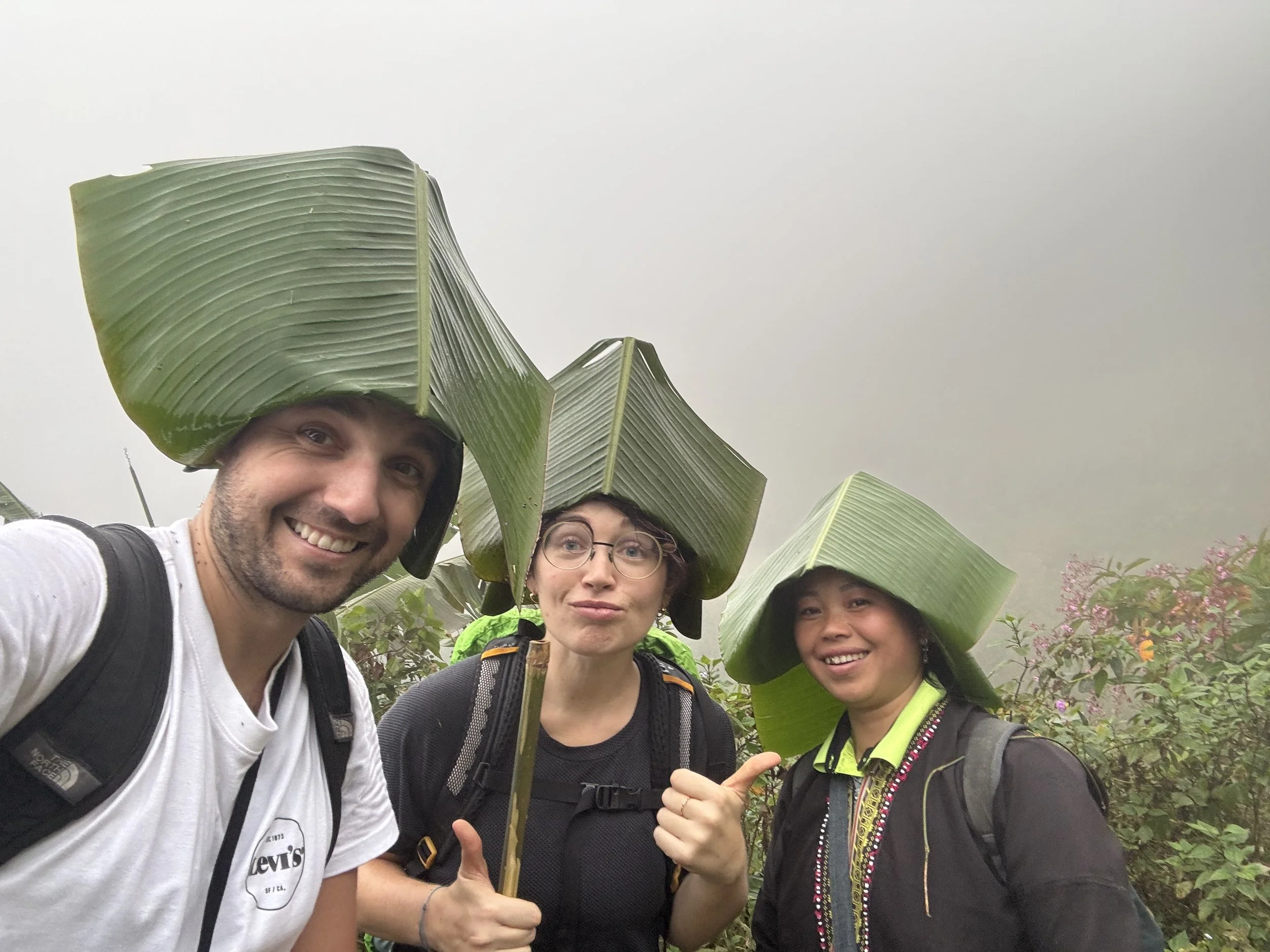 Travelers trekking in the rain with local ethnic guides in the mountains of Sapa.