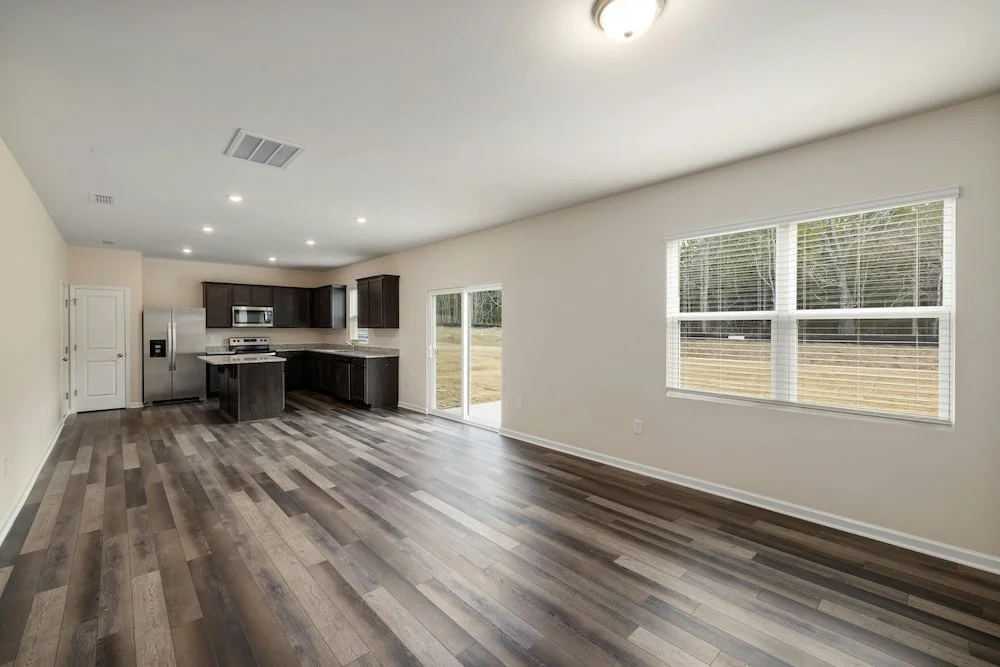 Professional real estate photography of a spacious open concept living area and kitchen with modern vinyl plank flooring in Ottawa by Charmcam.