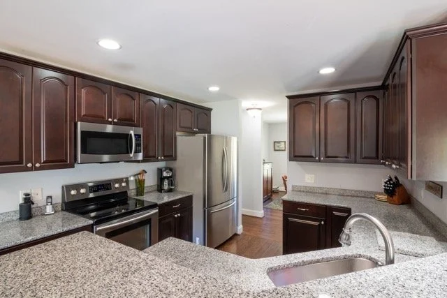 Professional real estate photography of a modern kitchen with dark wood cabinets in Ottawa by Charmcam.