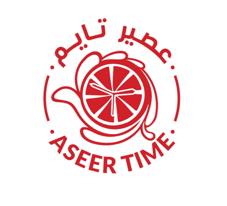 A logo featuring a teapot with a lemon slice inside, with text in Arabic and French around it reading "Together We Serve Time".