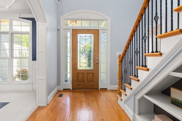 Professional real estate photography of an elegant home entrance foyer featuring a beautiful wooden front door and staircase in Ottawa by Charmcam.