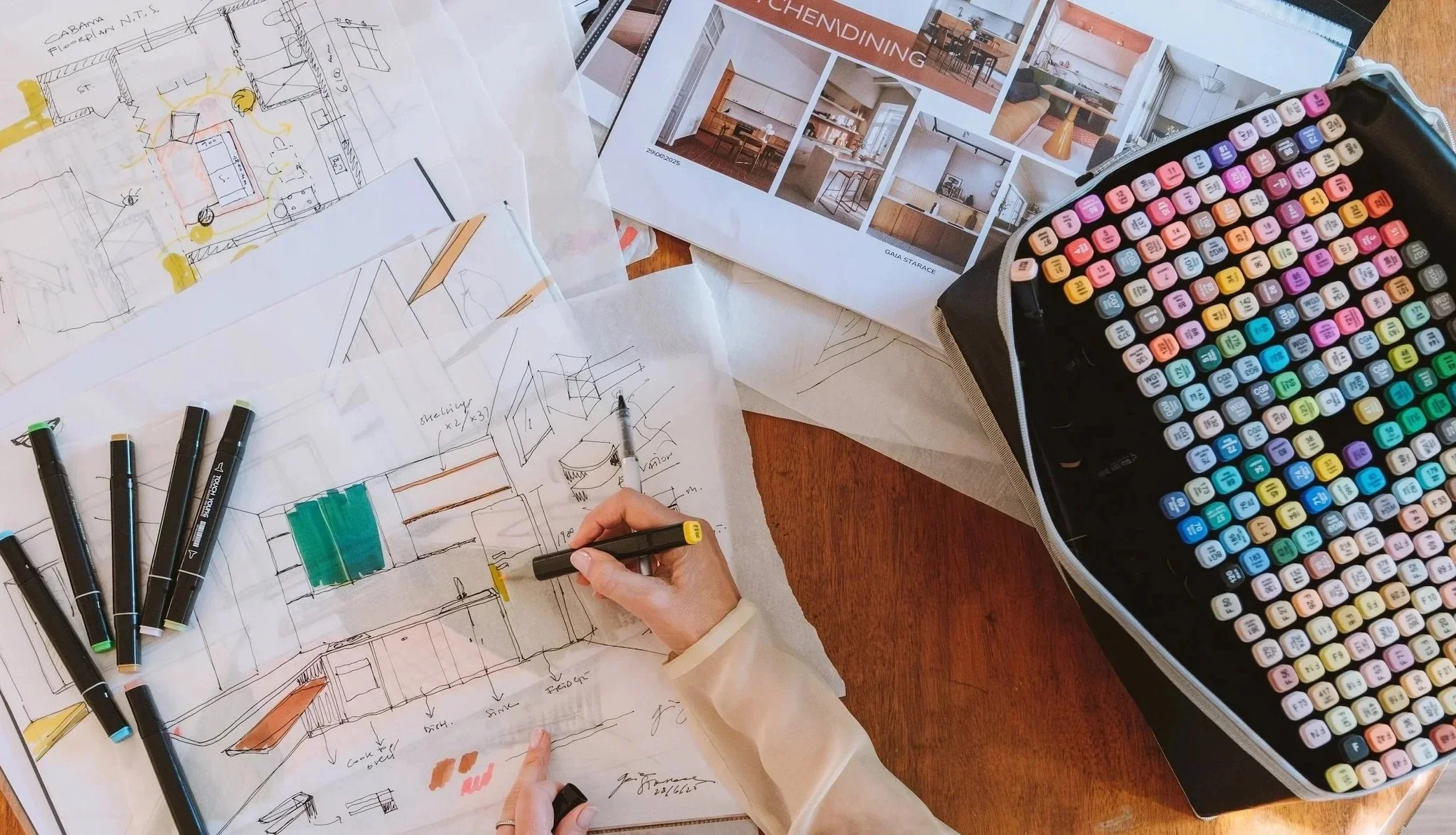 Architectural workspace with sketches, marker pens, interior design plans, and color markers for designing furniture and home interiors.