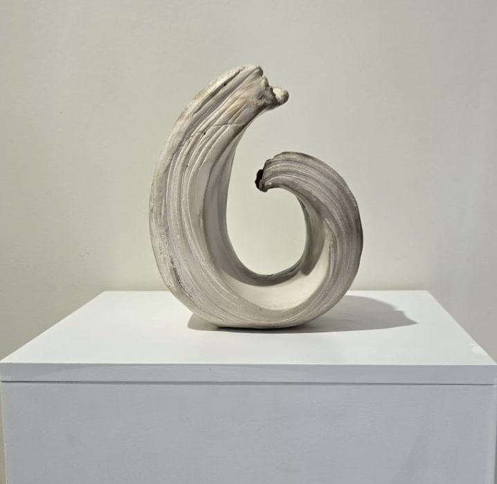 sculpture en céramique ou en argile de forme spiralée, posée sur un socle blanc dans une galerie d'art.
