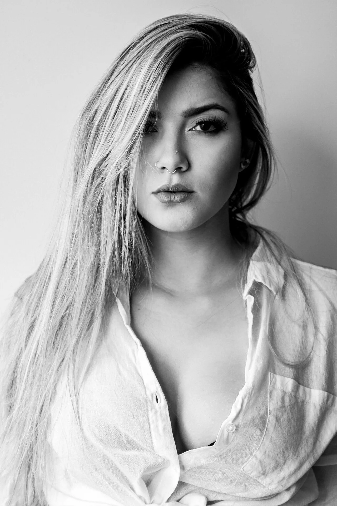 Black and white portrait of a woman with long hair, one eye showing, wearing a button-down shirt.