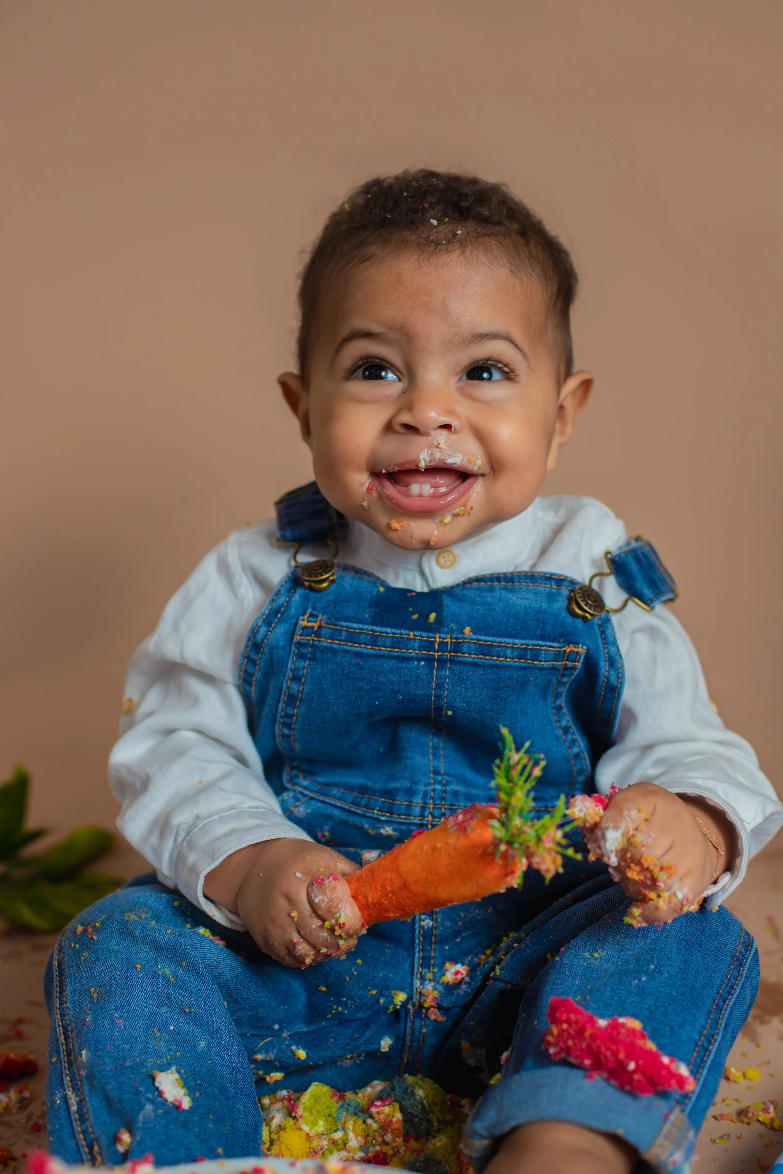 A beautiful milestones session with a baby boy holding a carrot and smiling