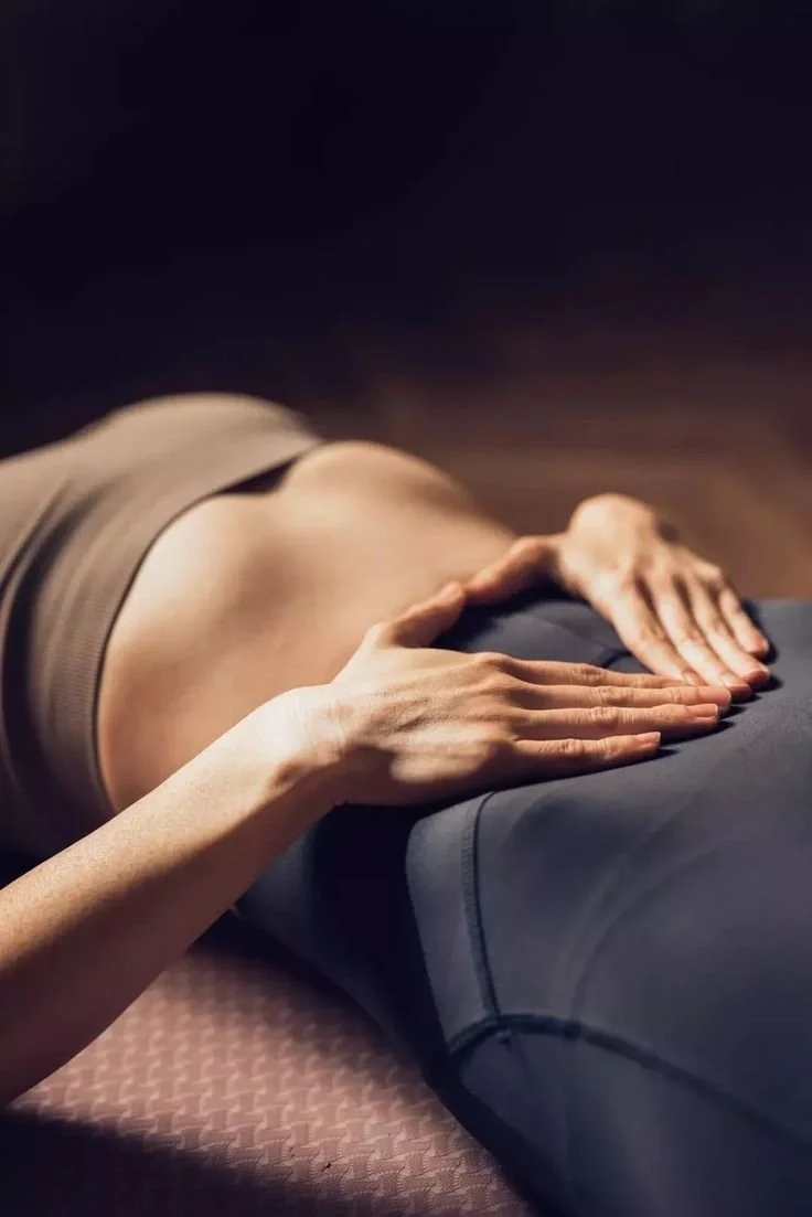 Close-up of a person receiving a massage, lying face down on a massage table with hands resting on their lower back.