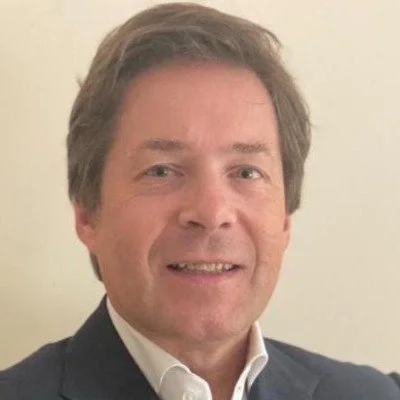 A man with brown hair and a white shirt smiling at the camera.