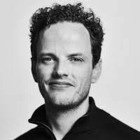 Two scientists in lab coats and safety goggles standing together in a laboratory.