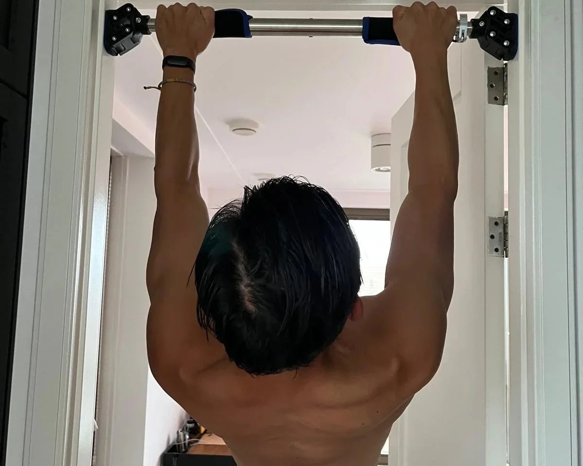 calisthenics beginner doing calisthenics training at home. his doing the exercise called scapula pull ups on his famba home pull up bar.
