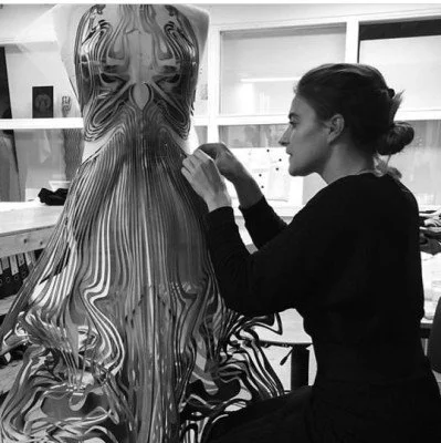 A woman working on a large, abstract marbled sculpture or fabric art in a studio.