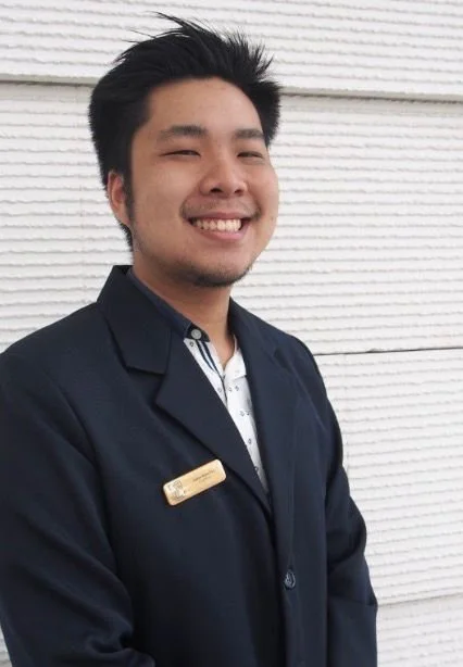 Young man in black blazer standing in front of a white background