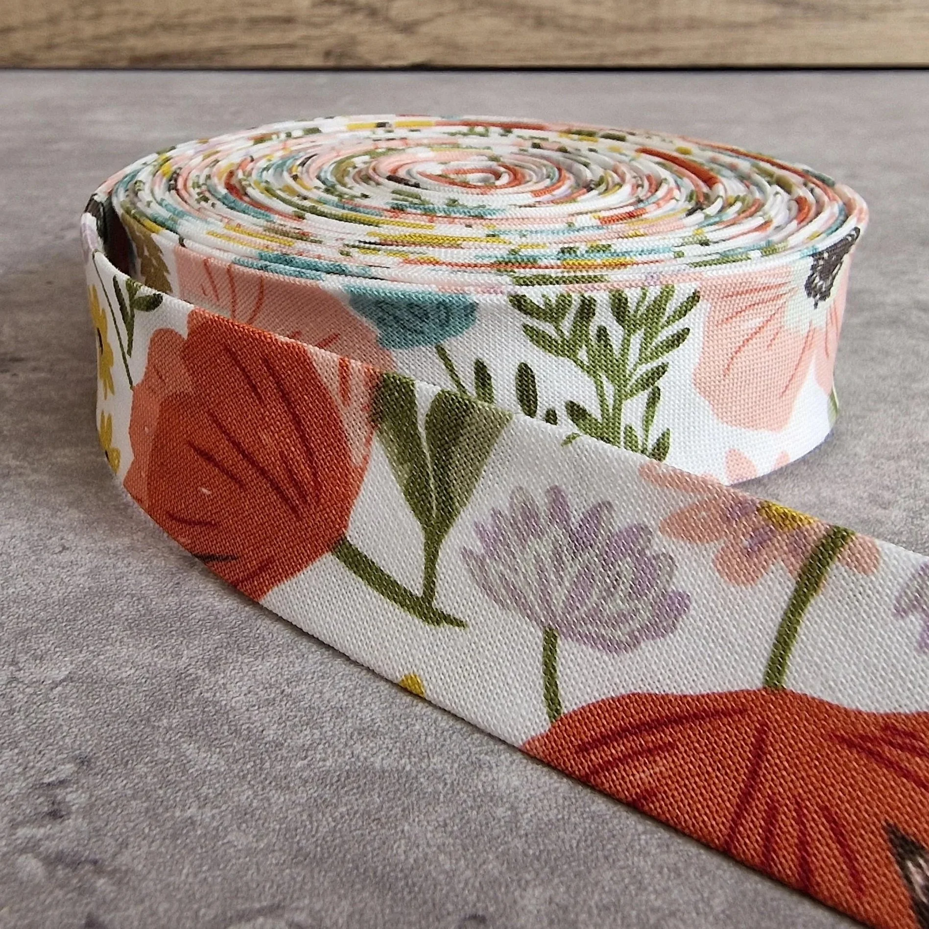 Makower white cotton bias binding tape with multicolour pattern, 25mm wide.