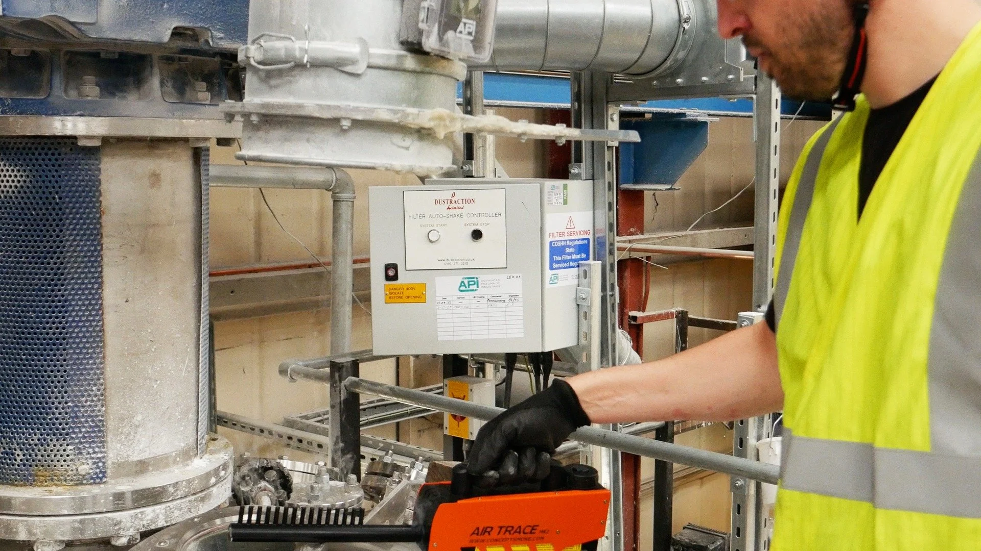 Engineer using test equipment beside industrial extraction equipment