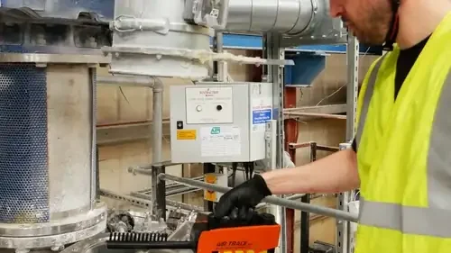 Engineer checking industrial extraction equipment with a handheld test instrument