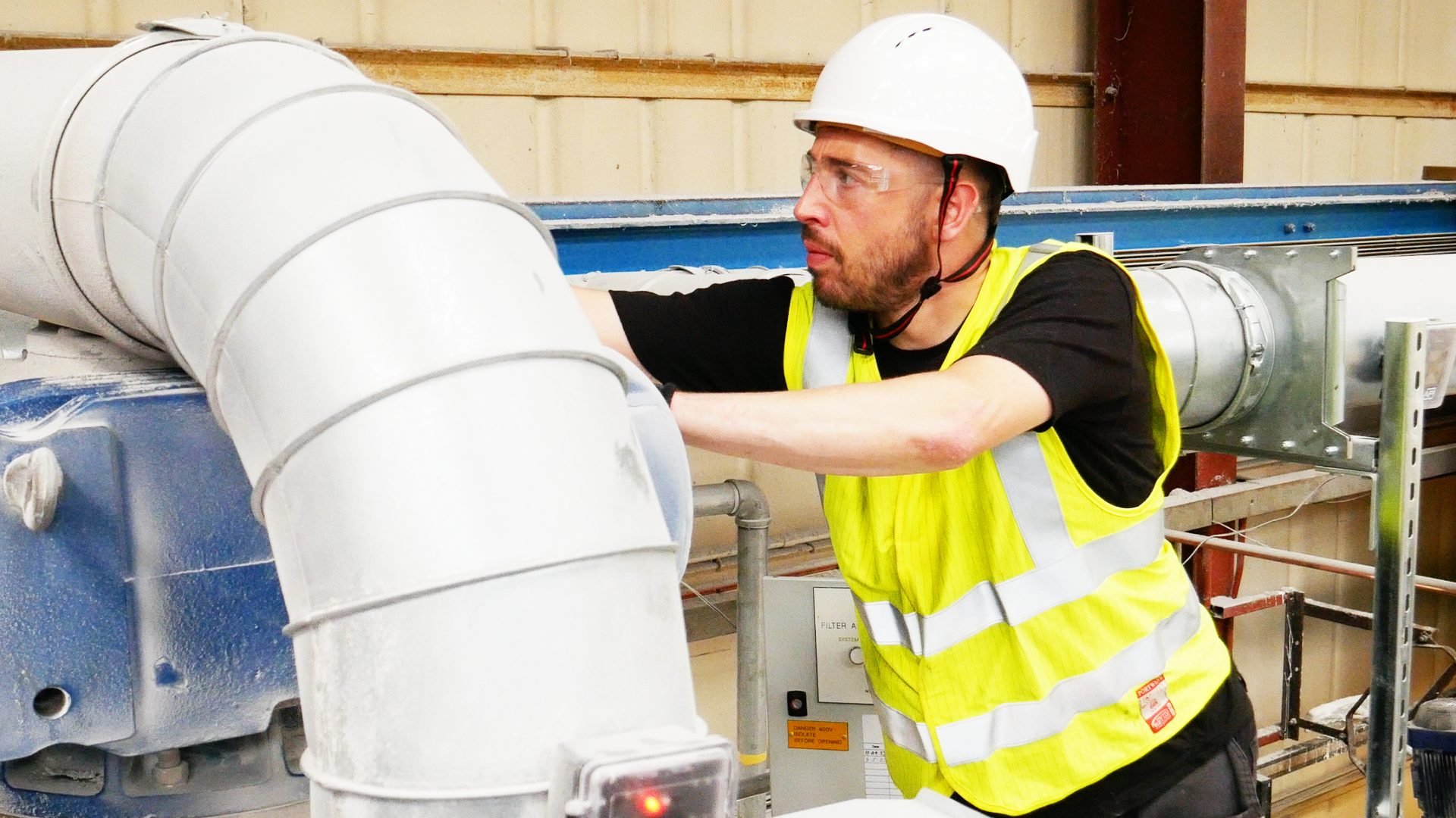 Engineer inspecting an industrial extraction system with metal ductwork