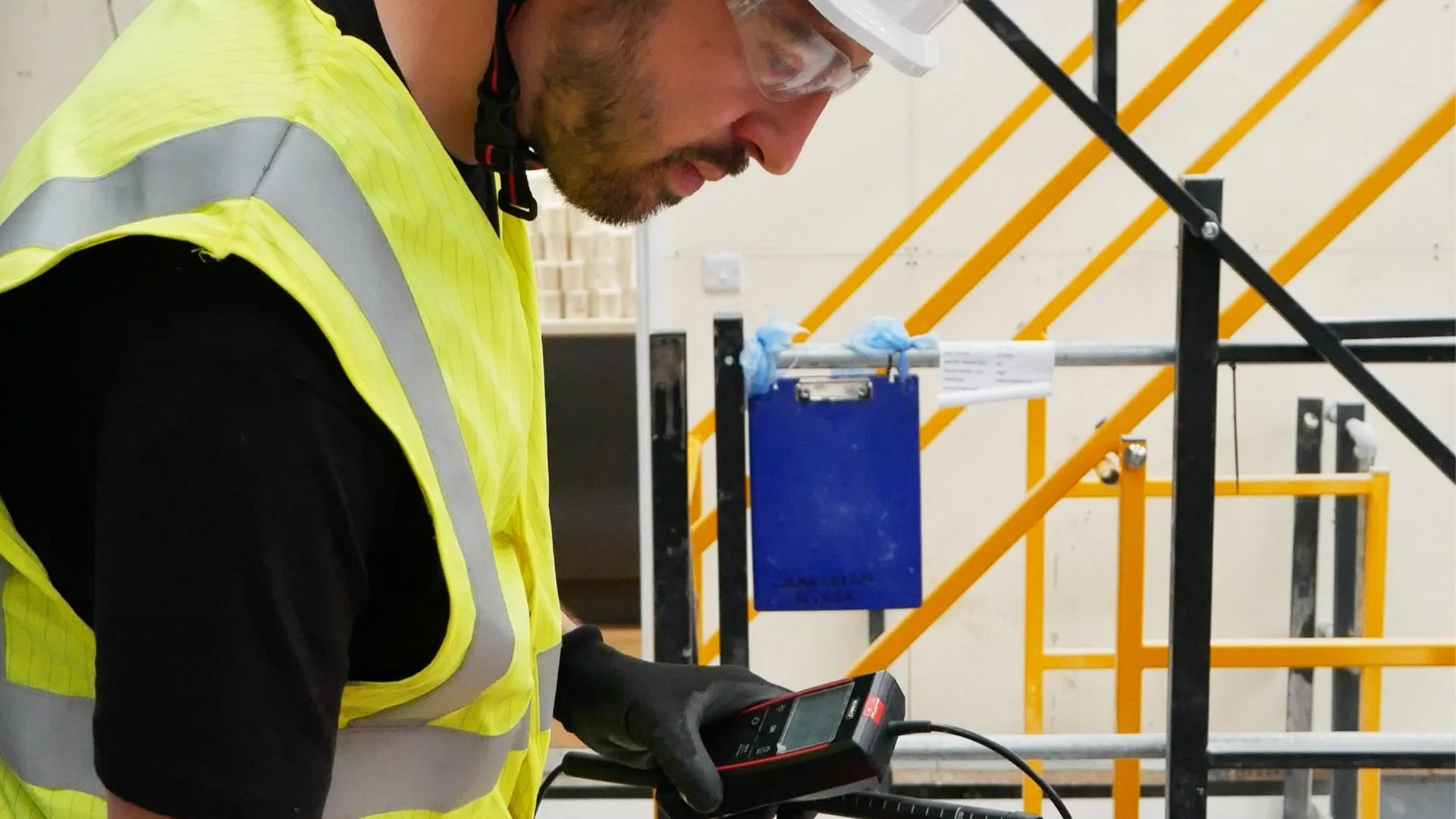 Engineer checking a handheld test instrument in an industrial workplace