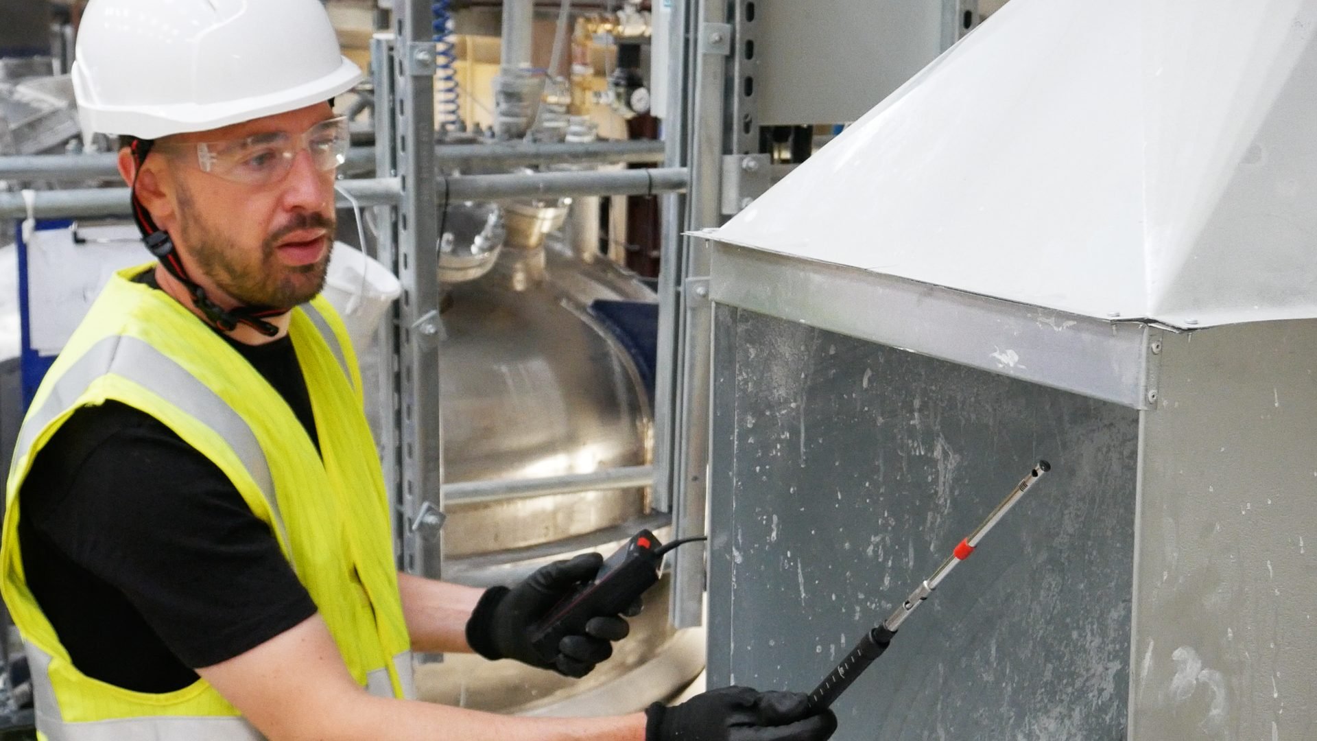 Engineer checking an extraction hood with a handheld probe