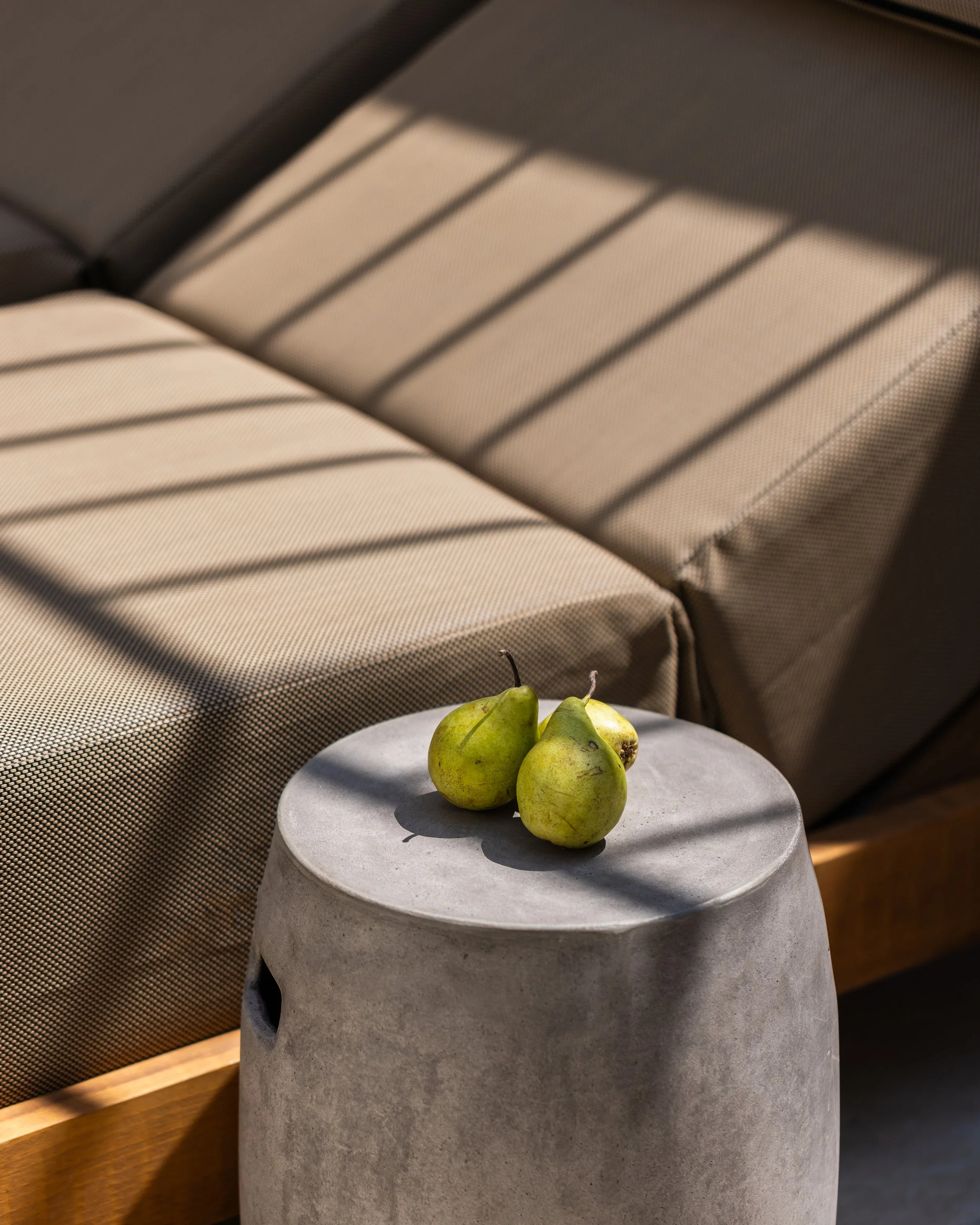 Three green pears on a side table next to a beige couch.