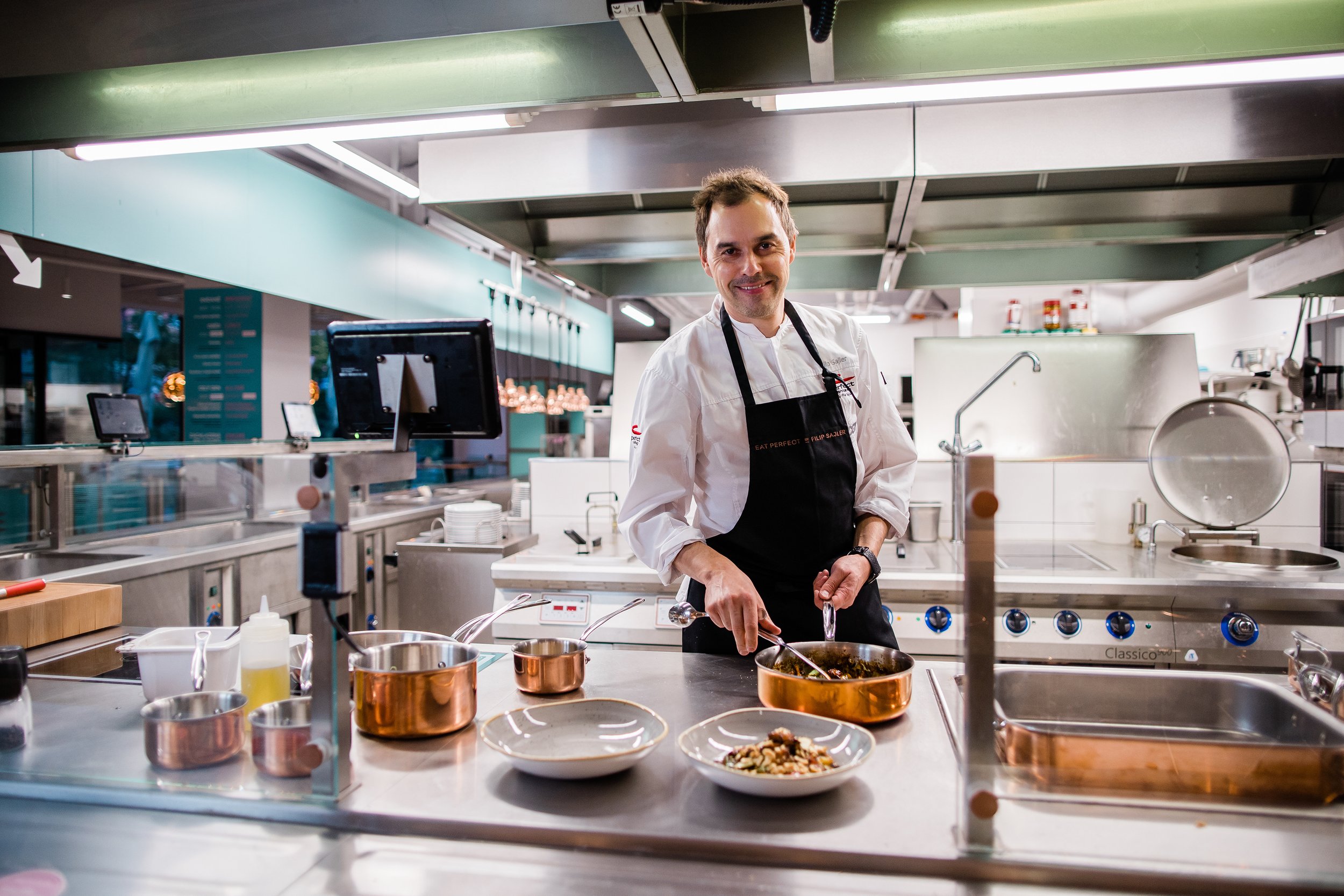 Professional chef cooking in a commercial kitchen with various cooking utensils and appliances around him. Personal branding and fine dining restaurant photography in Zürich, Zug, Bern, Lucerne, Basel, St. Gallen and across Switzerland.