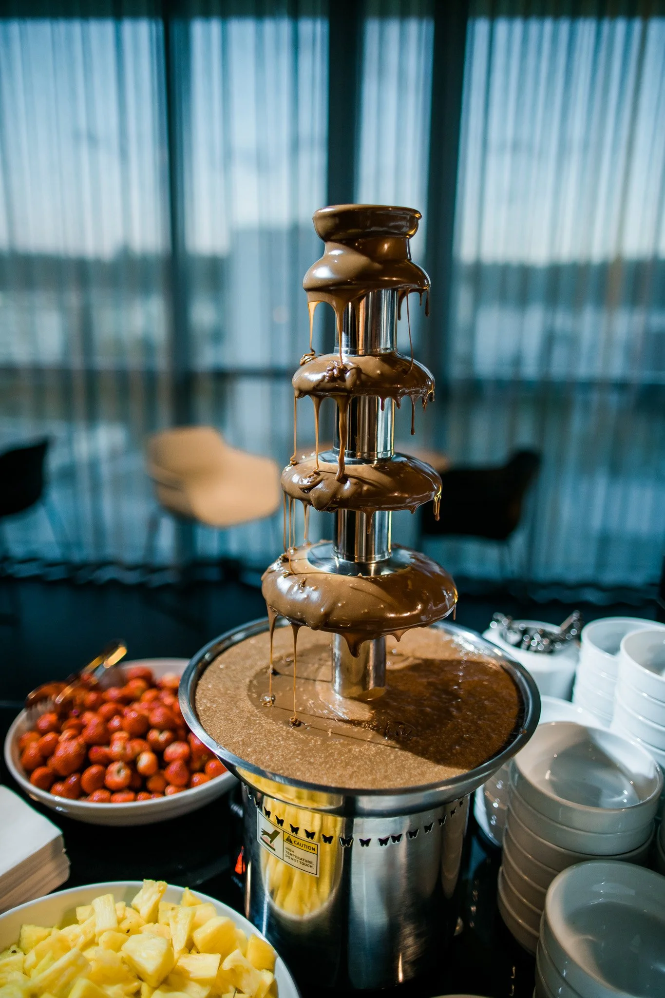 Chocolate fountain with strawberries and pineapple nearby. Catering and food photography in Zürich, Zug, Bern, Lucerne, Basel, St. Gallen and across Switzerland.