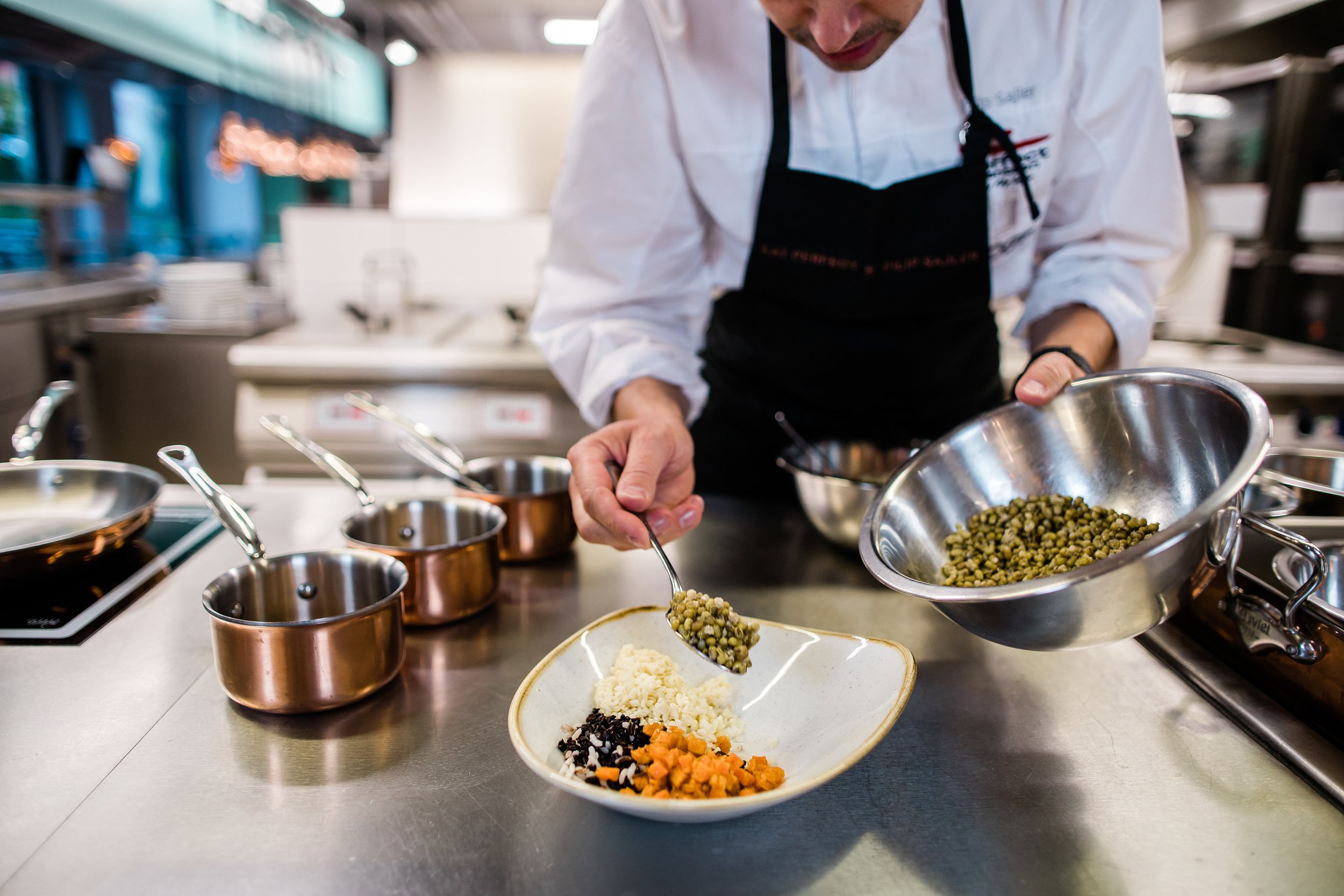 Chef preparing a dish with various vegetables and lentils in a professional kitchen. Personal branding and fine dining restaurant photography in Zürich, Zug, Bern, Lucerne, Basel, St. Gallen and across Switzerland.