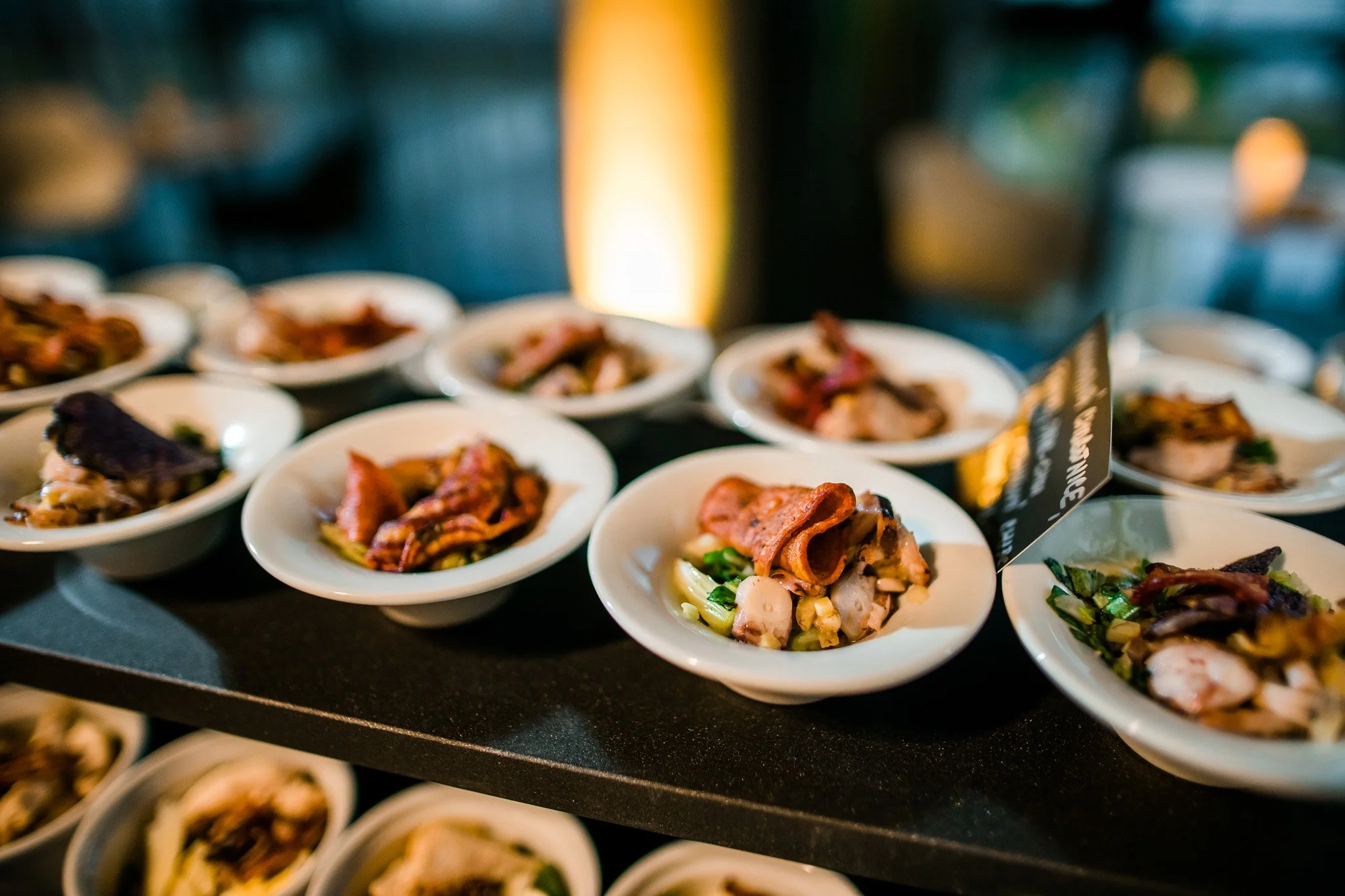 Assorted appetizer bites served in small white bowls on a black display table. Catering and food photography in Zürich, Zug, Bern, Lucerne, Basel, St. Gallen and across Switzerland.