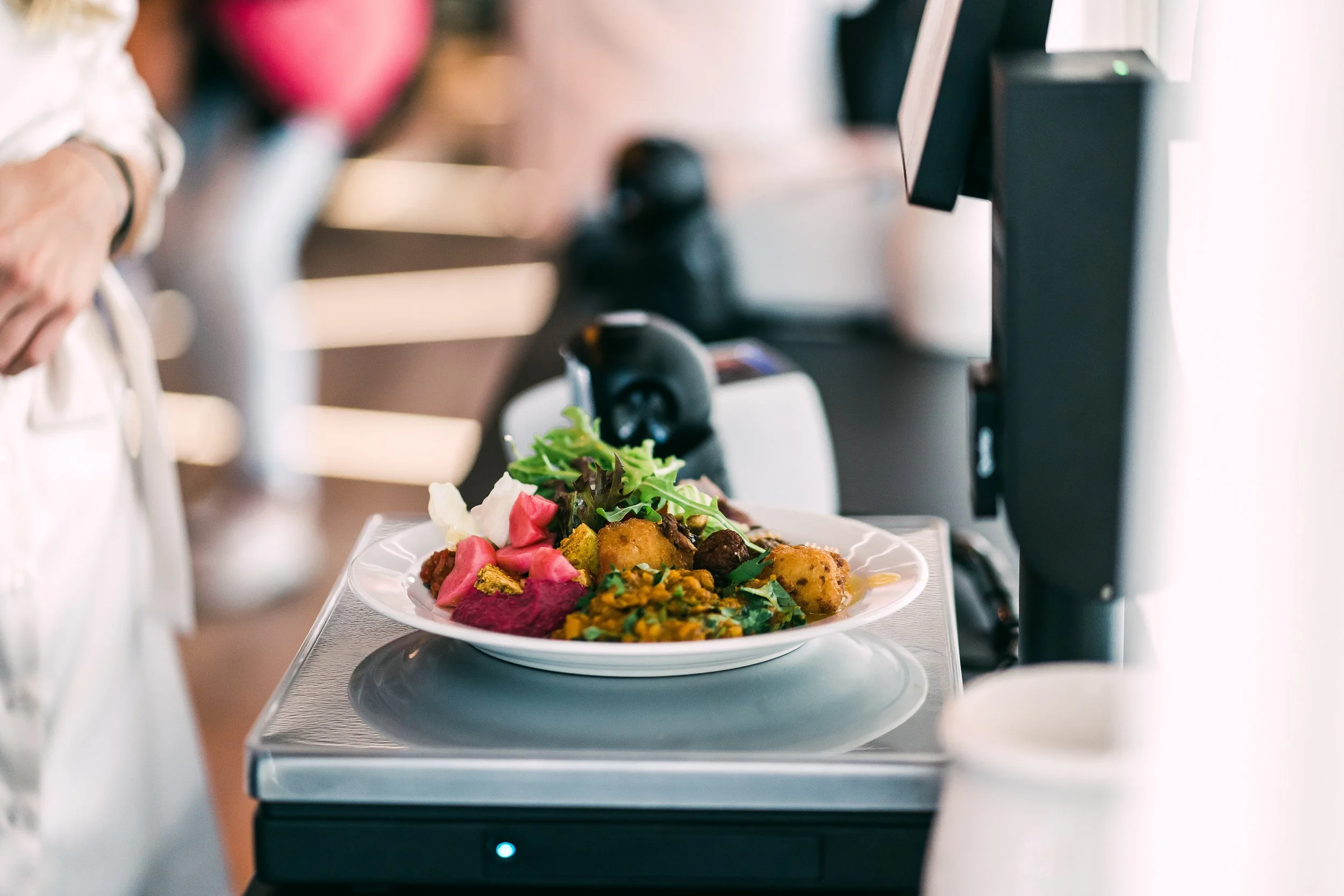 Plate of colorful food on a conveyor belt in a restaurant or food service setting. Restaurant interior photography in Zürich, Zug, Bern, Lucerne, Basel, St. Gallen and across Switzerland.
