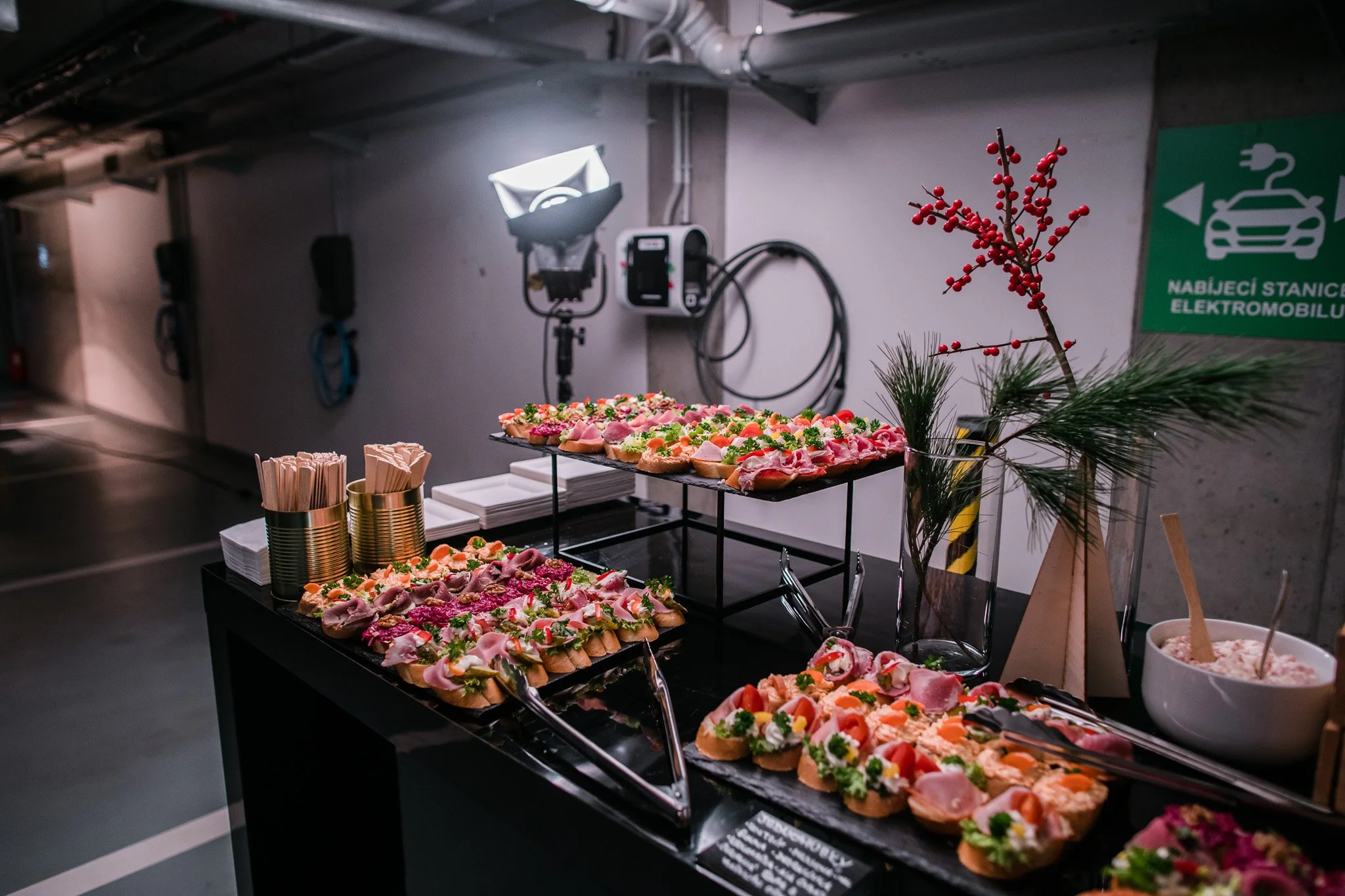 An assortment of decorated open-faced sandwiches on a black table, with snacks and holiday decorations, in a parking garage or underground area. Catering and food photography in Zürich, Zug, Bern, Lucerne, Basel, St. Gallen and across Switzerland.
