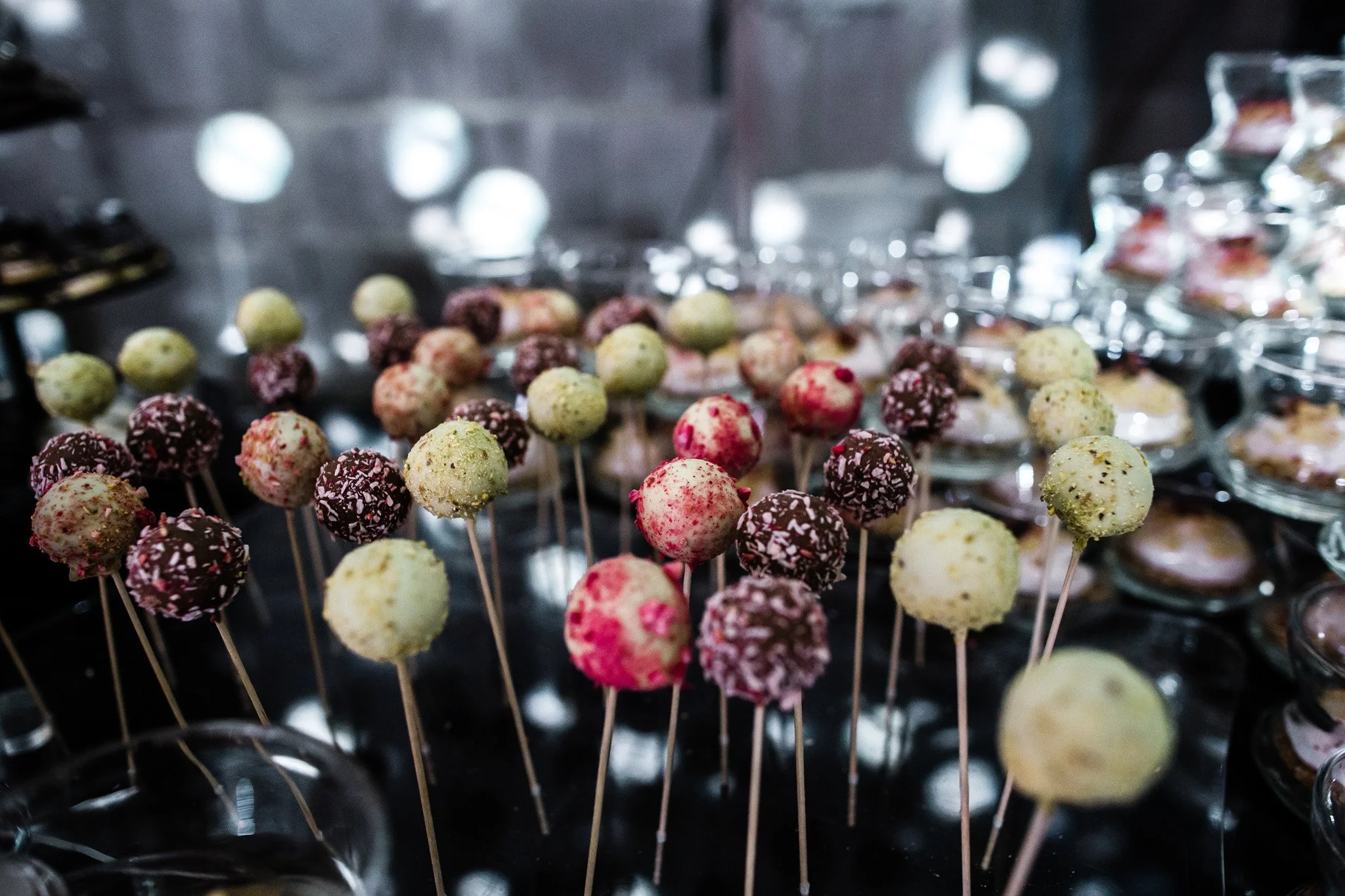 Assorted cake pops on sticks in various colors and toppings displayed on a table at a dessert buffet. Catering, culinary and food photography in Zürich, Zug, Bern, Lucerne, Basel, St. Gallen and across Switzerland.