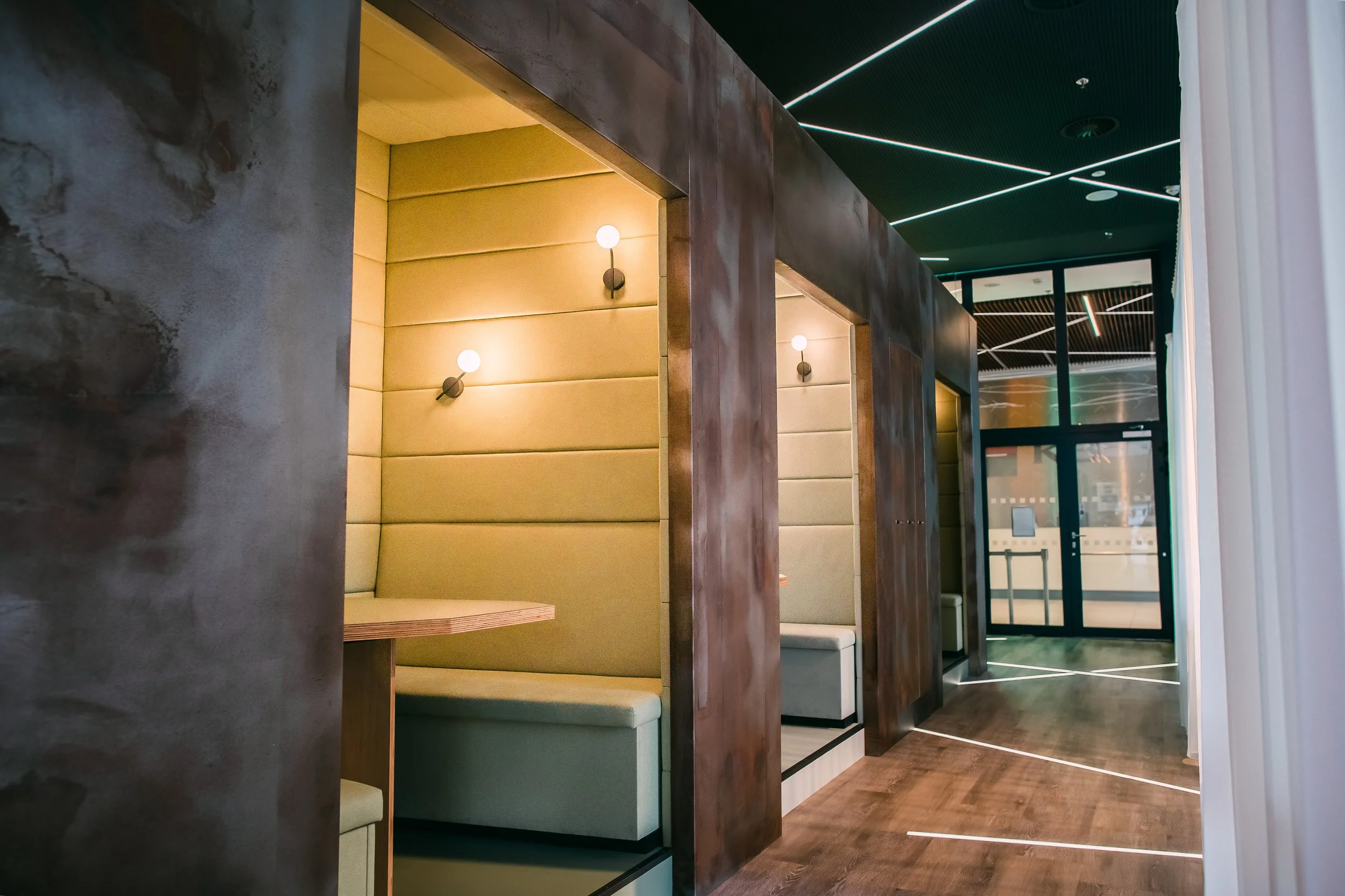 Interior of a modern restaurant or cafe with cozy booth seating, beige upholstered walls, wood finishes, and sleek lighting on the ceiling. Restaurant interior photography in Zürich, Zug, Bern, Lucerne, Basel, St. Gallen and across Switzerland.