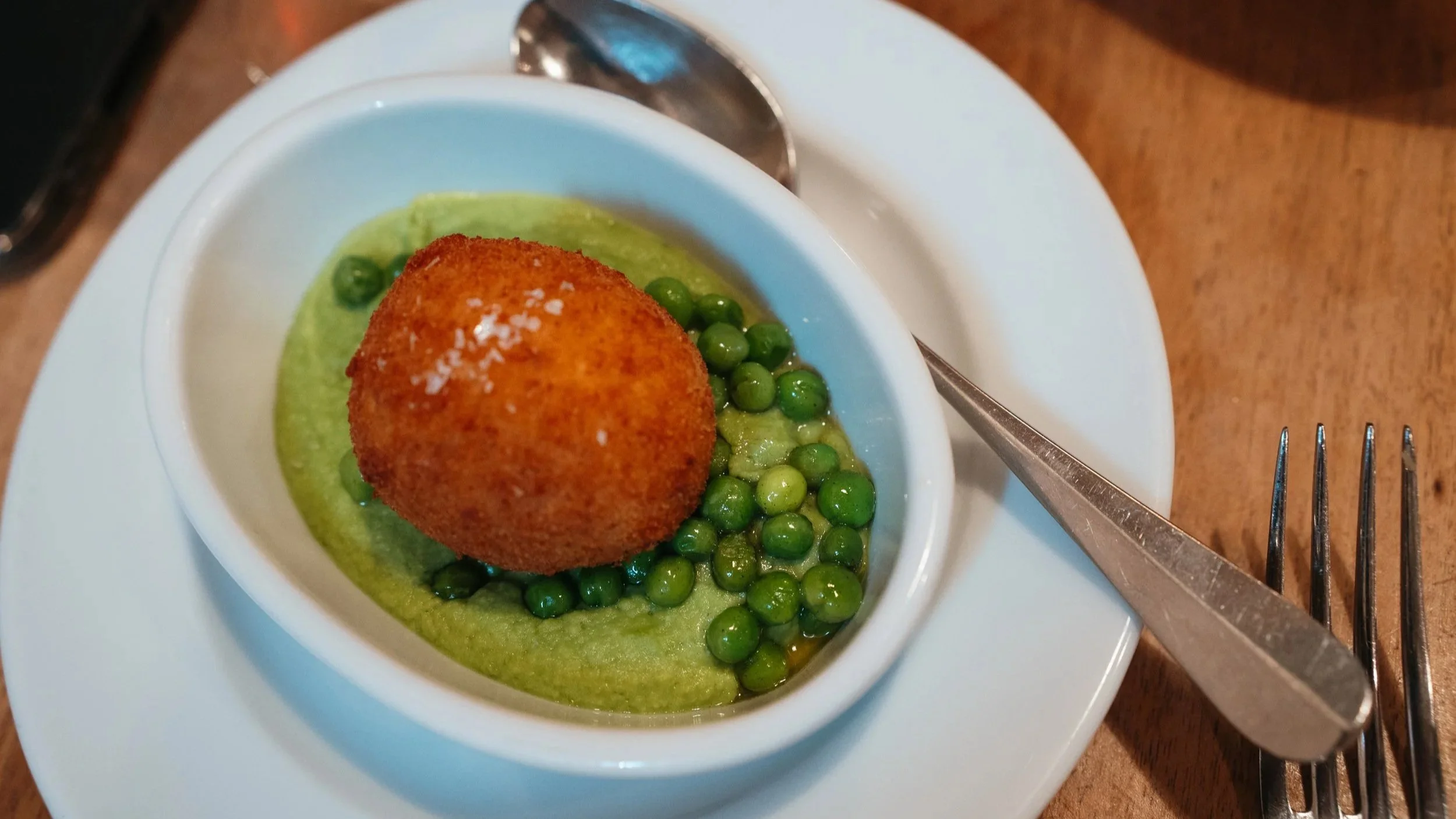 Breaded organic egg with young peas and pea cream in dinner restaurant Lotti in Zurich, Switzerland.