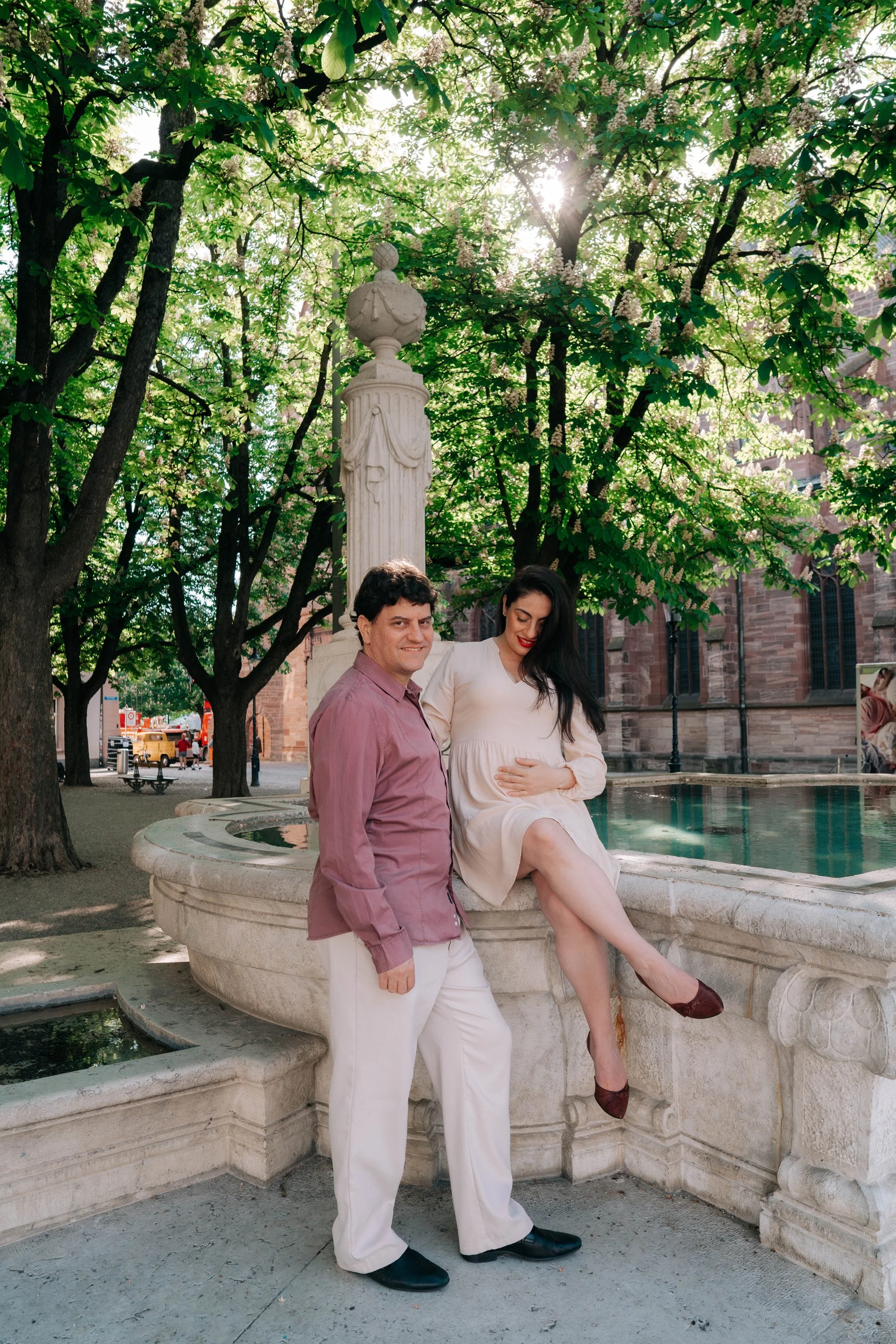 Romantic maternity portrait at fountain surrounded by old architecture in Basel, Switzerland.