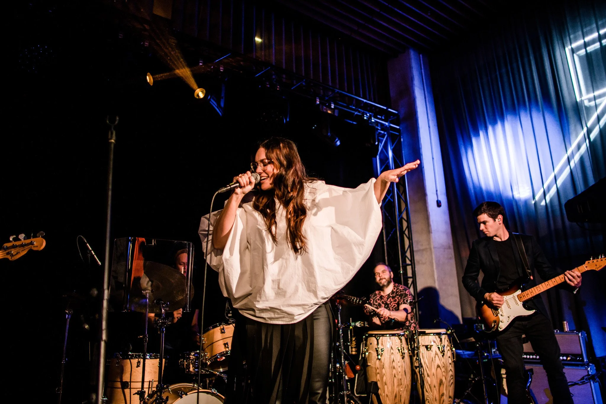 Singer performing with band on stage, surrounded by musical instruments and stage lighting. Concert and singer photography in Zürich, Zug, Bern, Lucerne, Basel, St. Gallen and across Switzerland.