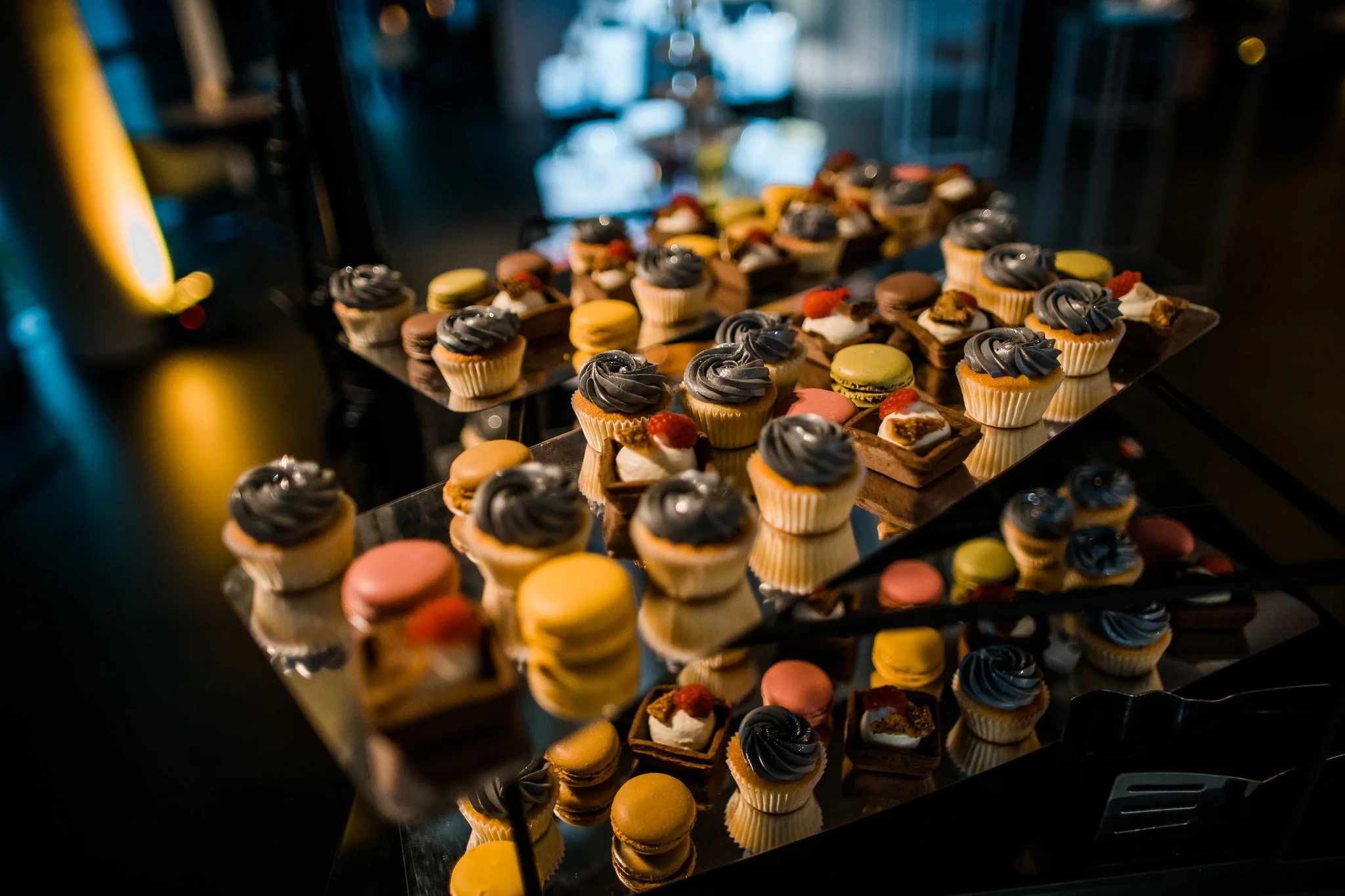Assorted cupcakes and pastries on display on a glass tray at a dessert buffet. Catering and food photography in Zürich, Zug, Bern, Lucerne, Basel, St. Gallen and across Switzerland.