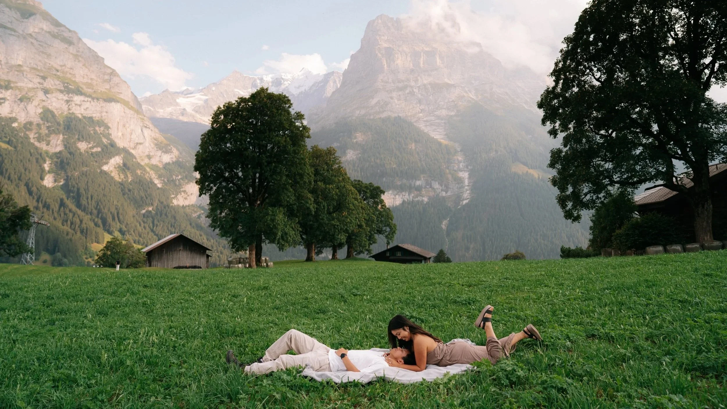 Candid cinematic moments of a couple laughing together in the picturesque village of Grindelwald with the Swiss Alps glowing in soft golden evening light.