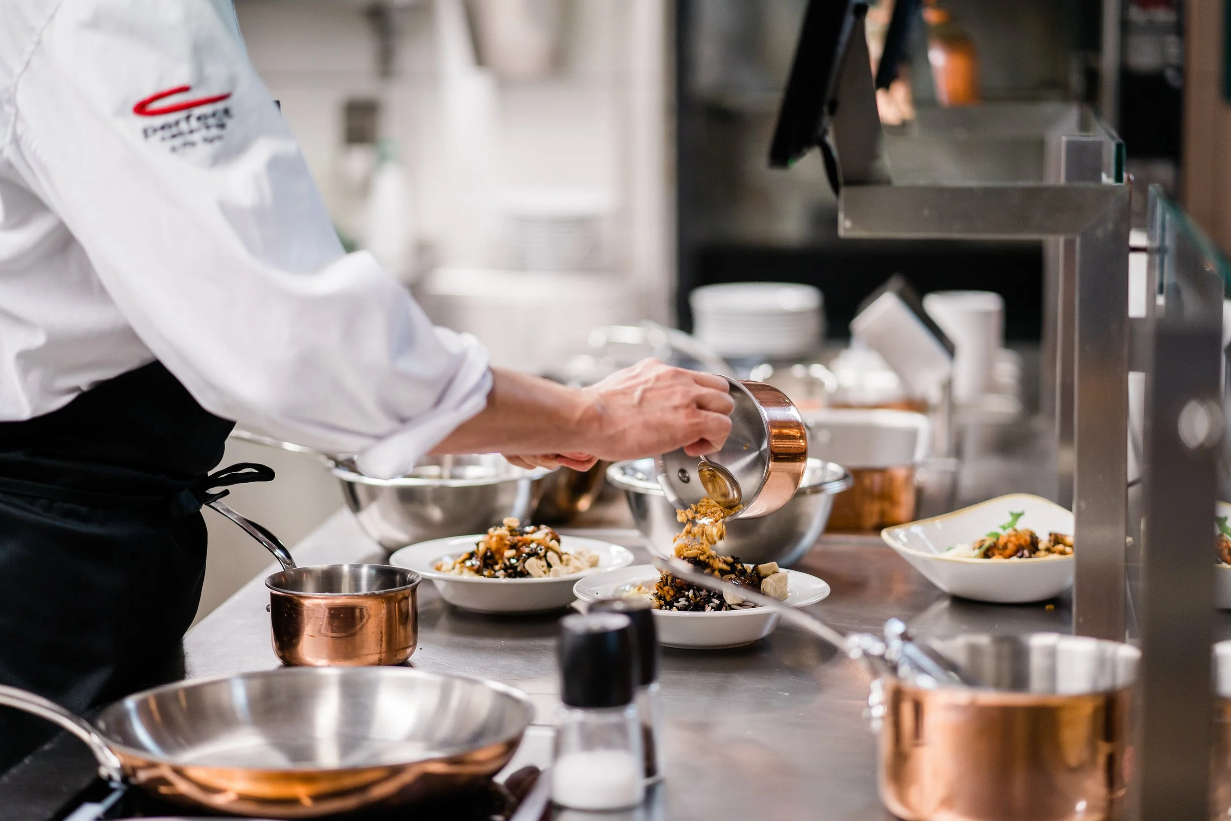 A chef in a white uniform plating food in a professional kitchen. Personal branding and fine dining restaurant photography in Zürich, Zug, Bern, Lucerne, Basel, St. Gallen and across Switzerland.