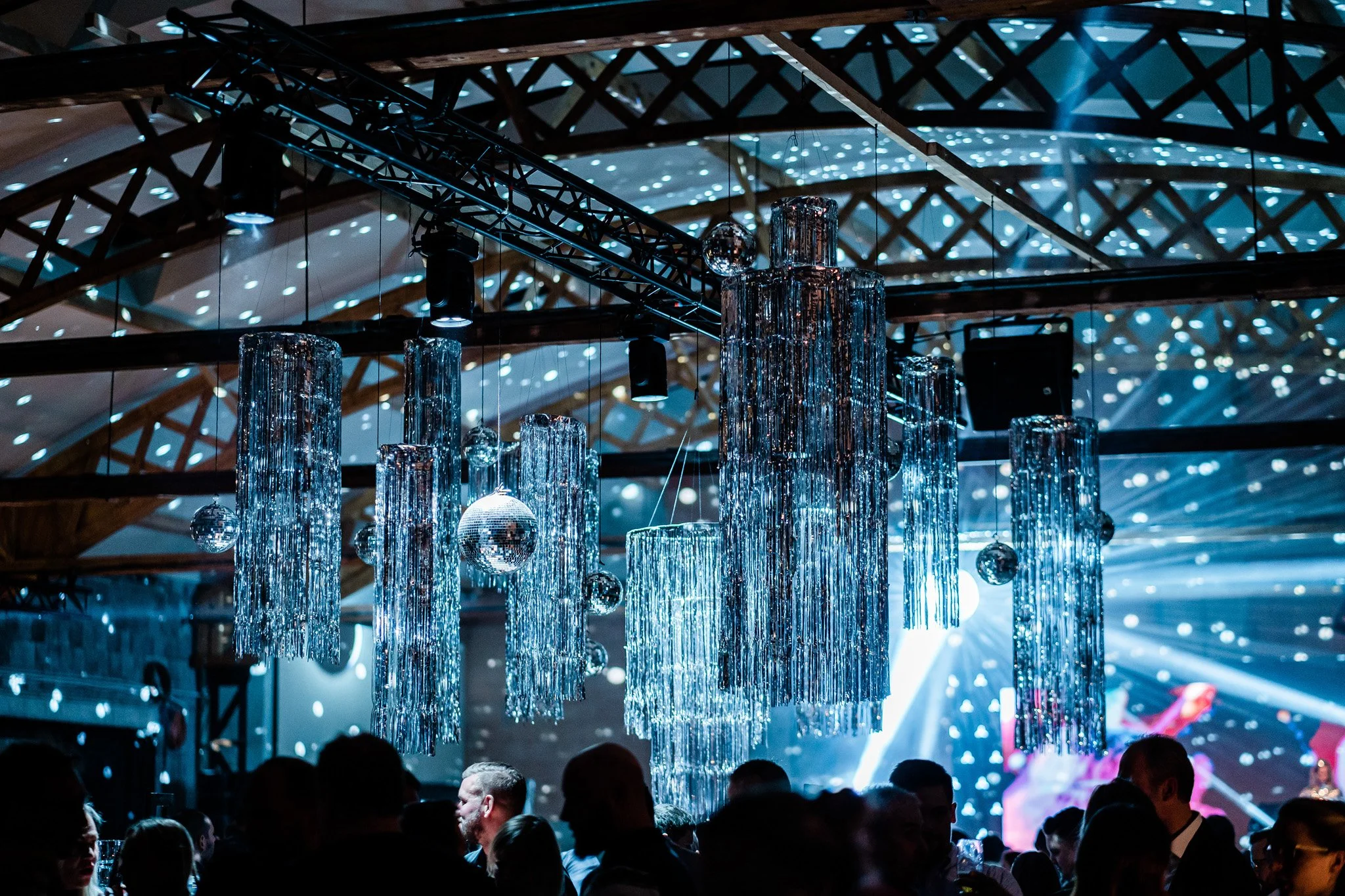 Elegant party scene with hanging crystal chandeliers and disco balls in a large, decorated event space filled with people. Concert photography in Zürich, Zug, Bern, Lucerne, Basel, St. Gallen and across Switzerland.